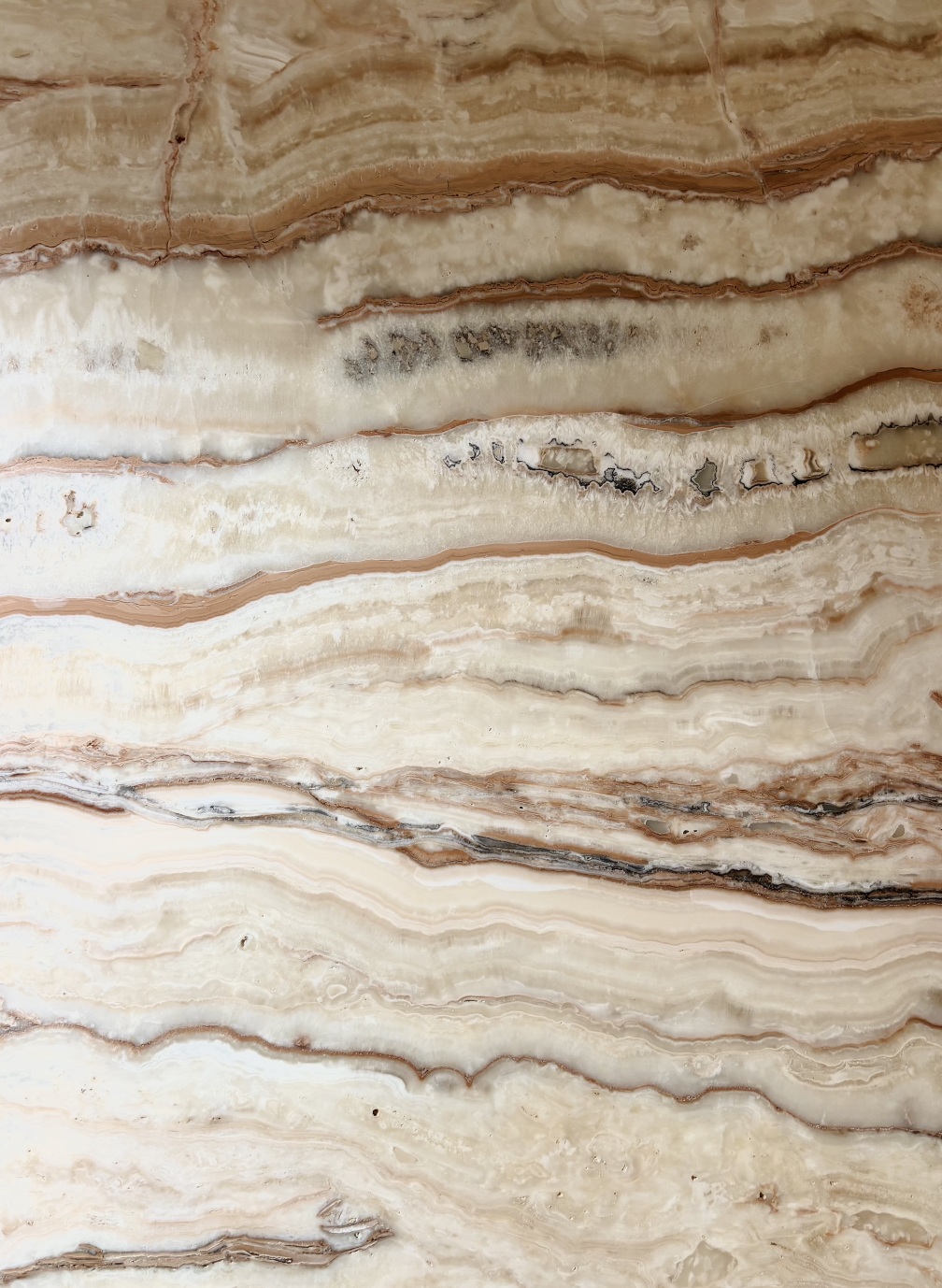 Close-up of a marble surface with beige and brown layered patterns.