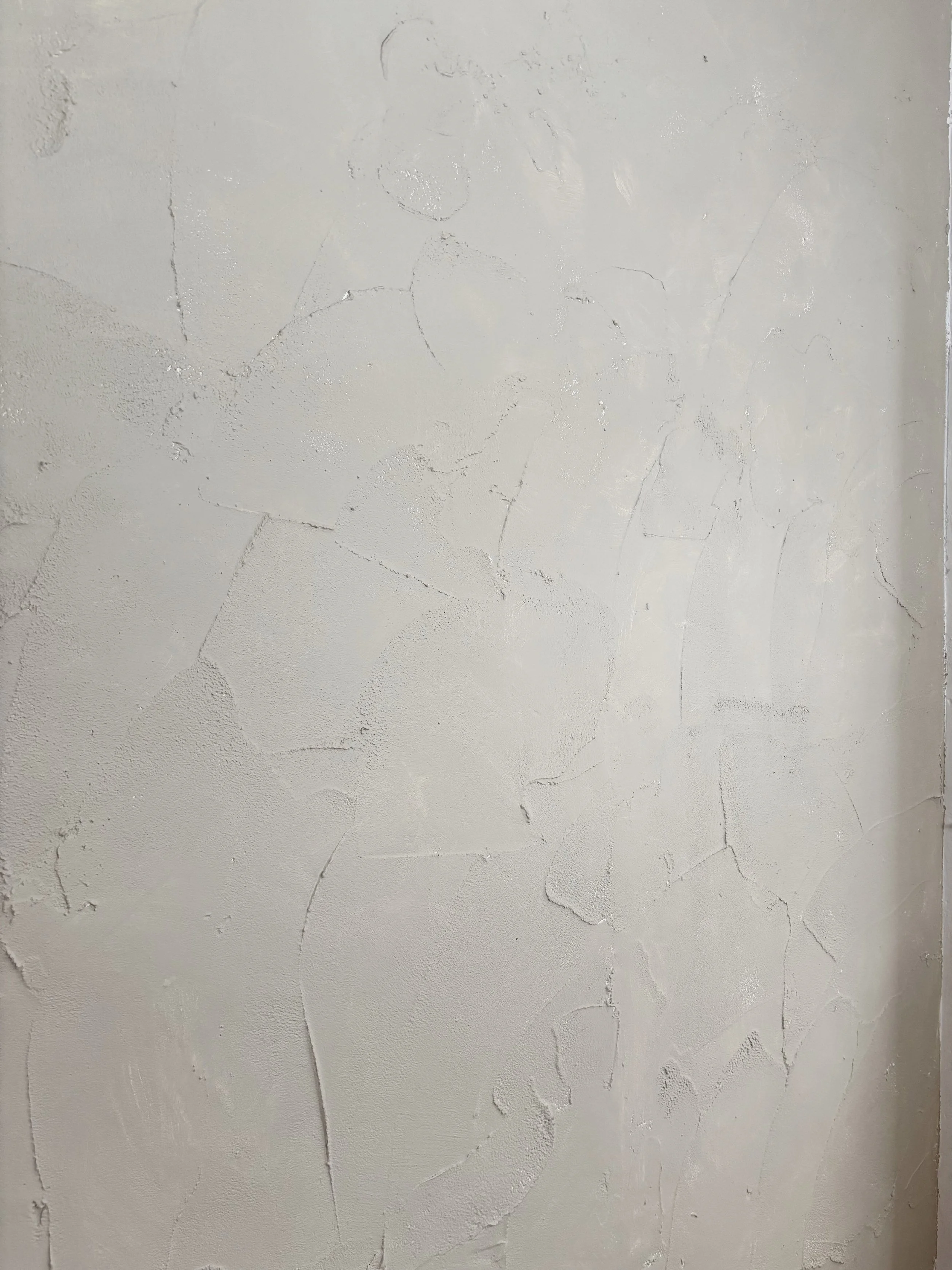 Close-up of a textured beige wall with cracks and uneven surface.