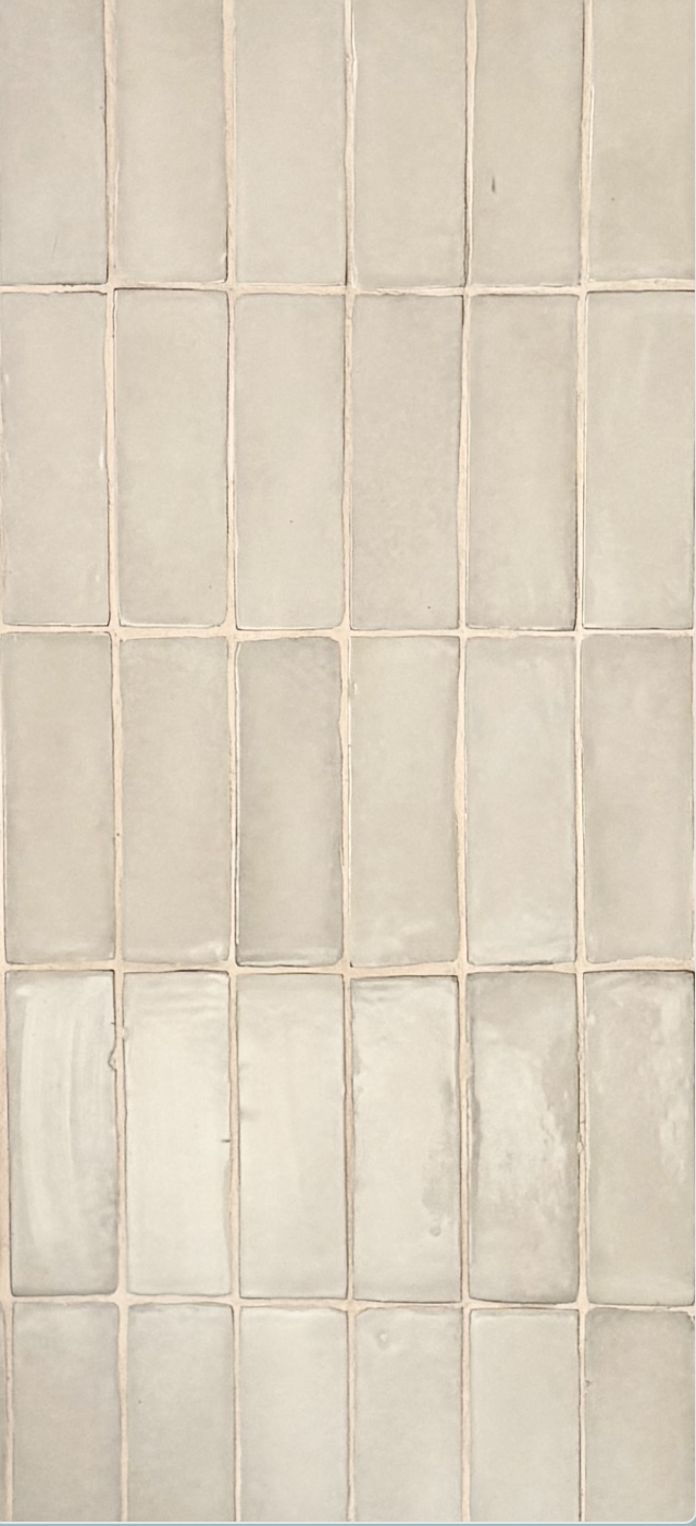 Close-up of a tiled wall with beige square tiles and light-colored grout lines.