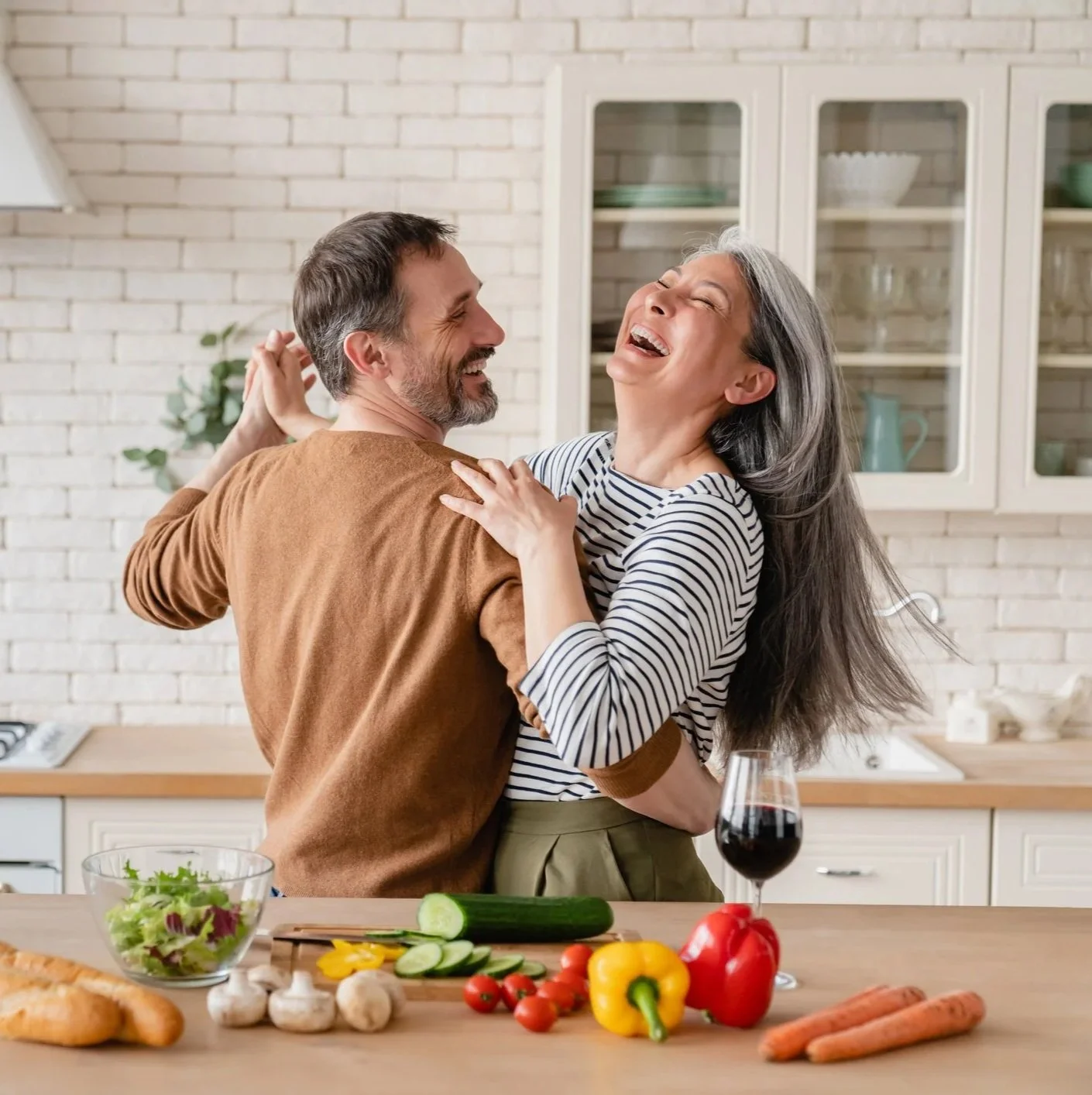 Couple laughing together while cooking, showing emotional connection and joy in a healthy relationship
