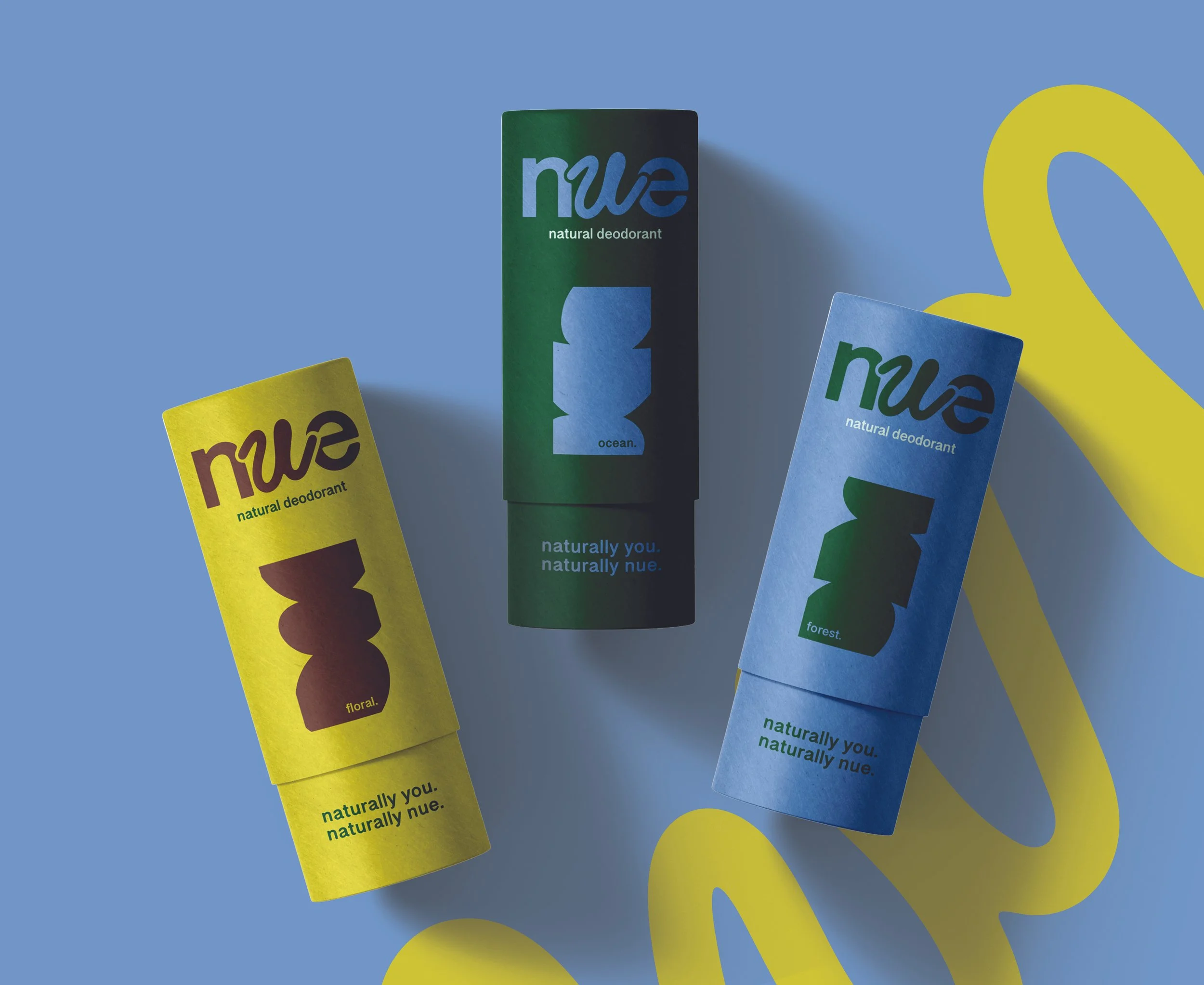 Three cylindrical containers of natural deodorant with colorful packaging on a light blue background with yellow abstract shapes. Each container has the 'nue' logo and a different label: 'flora,' 'ocean,' and 'forest.'