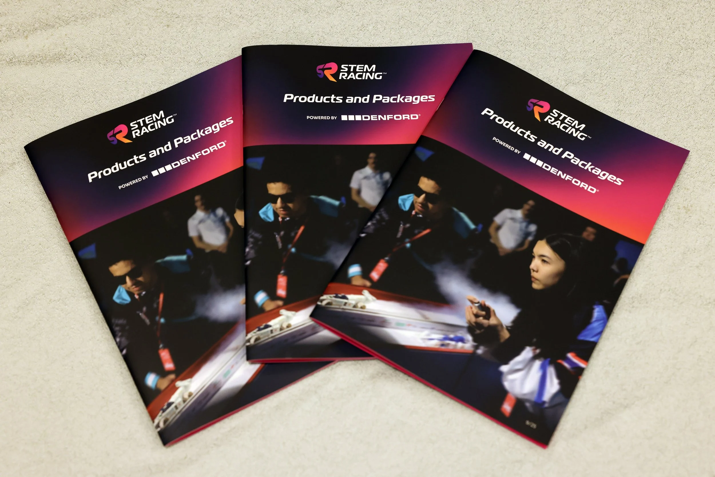 Three STEM Racing brochures for products and packages, featuring a dark background with a woman and a man in racing gear and sunglasses, with the title "Products and Packages" and "Powered by DENFORD".