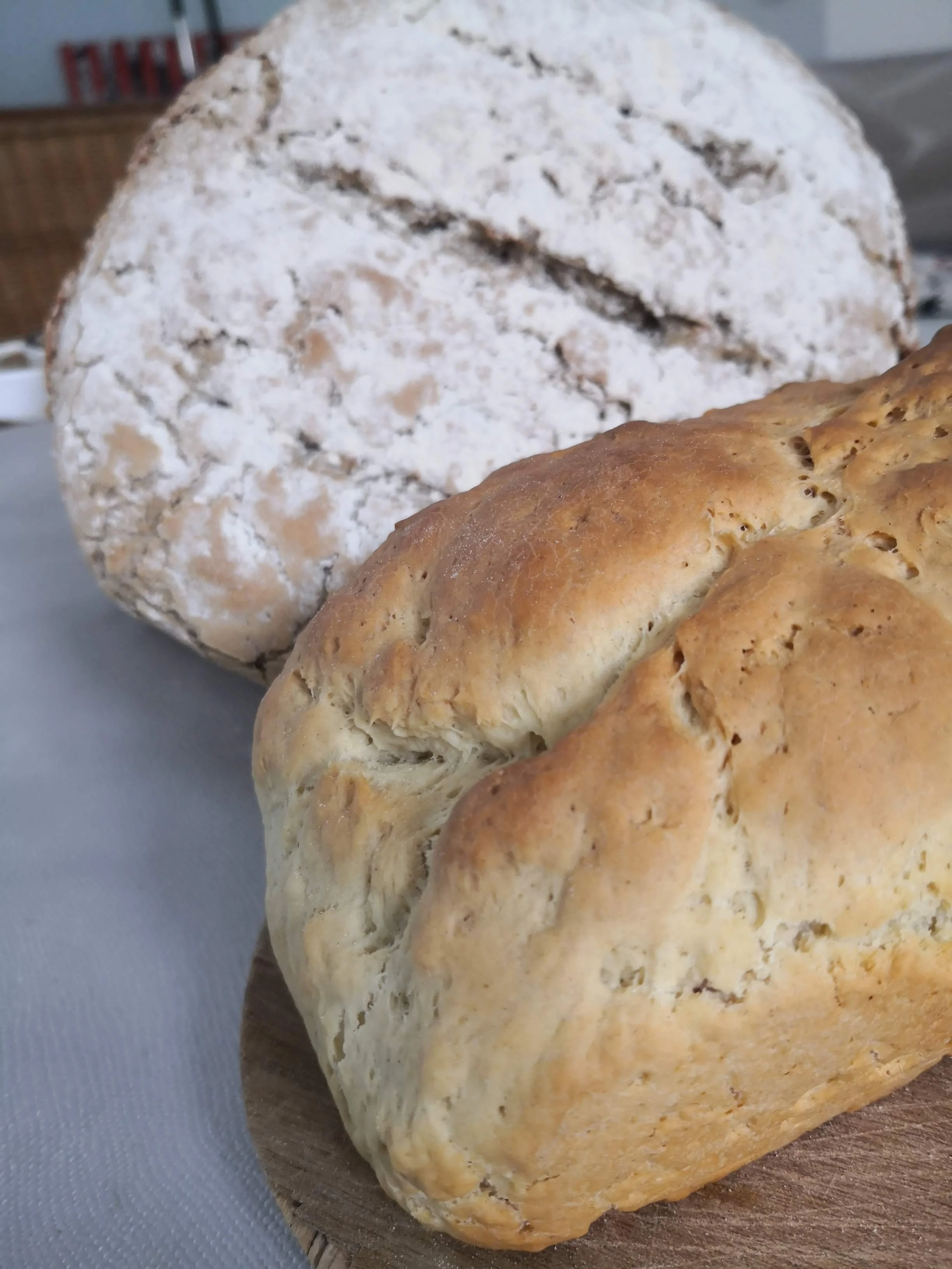 Deux pains, recouverts de farine, sur une planche en bois.