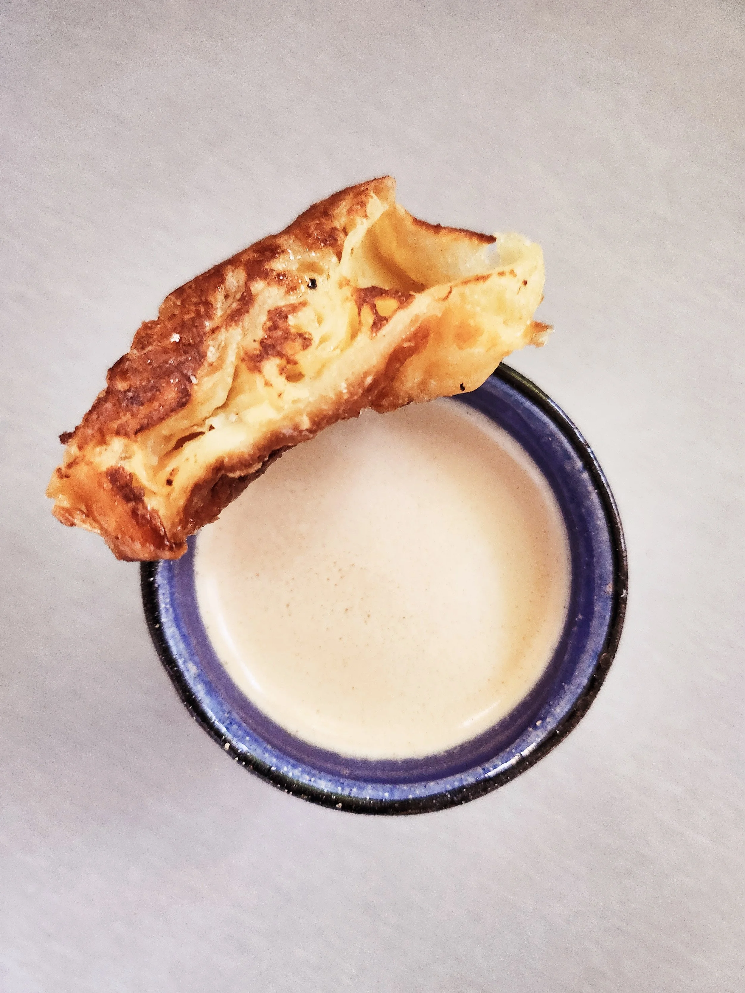 Un chai avec une doughnut à la cannelle sur le rebord.
