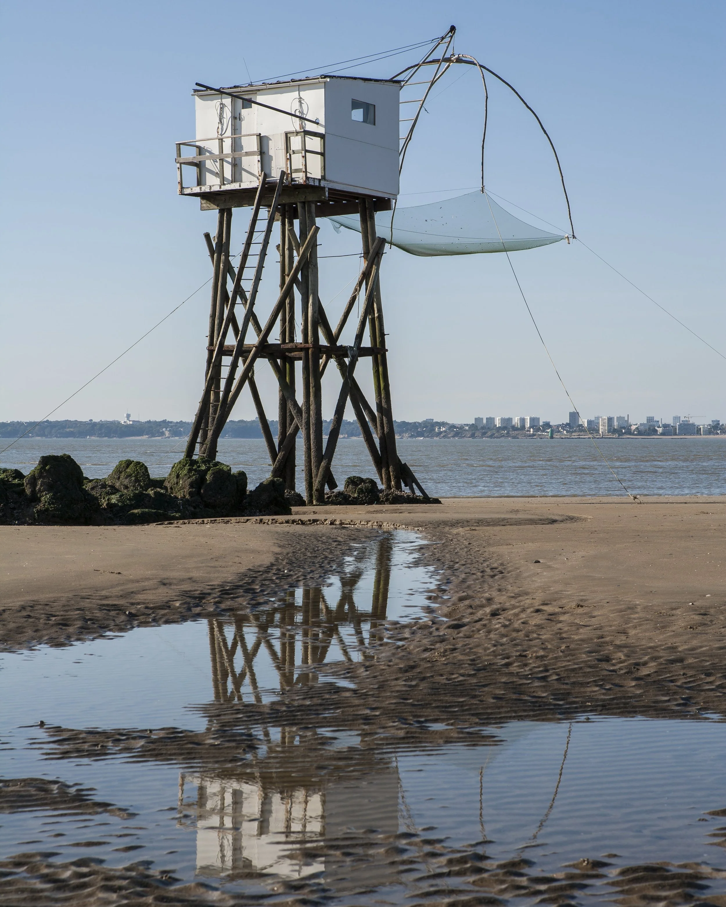 Une pêcherie est maisonnette de pêche typique de l'estuaire, perchée sur une structure en bois avec un filet suspendu appelé carrelet, sur le bord de mer, fond de côte urbaine ville de Saint-Nazaire.