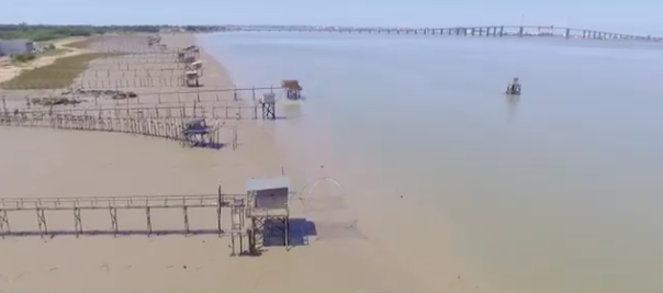 Vastes plages avec des levages de sable et un pont en arrière-plan.