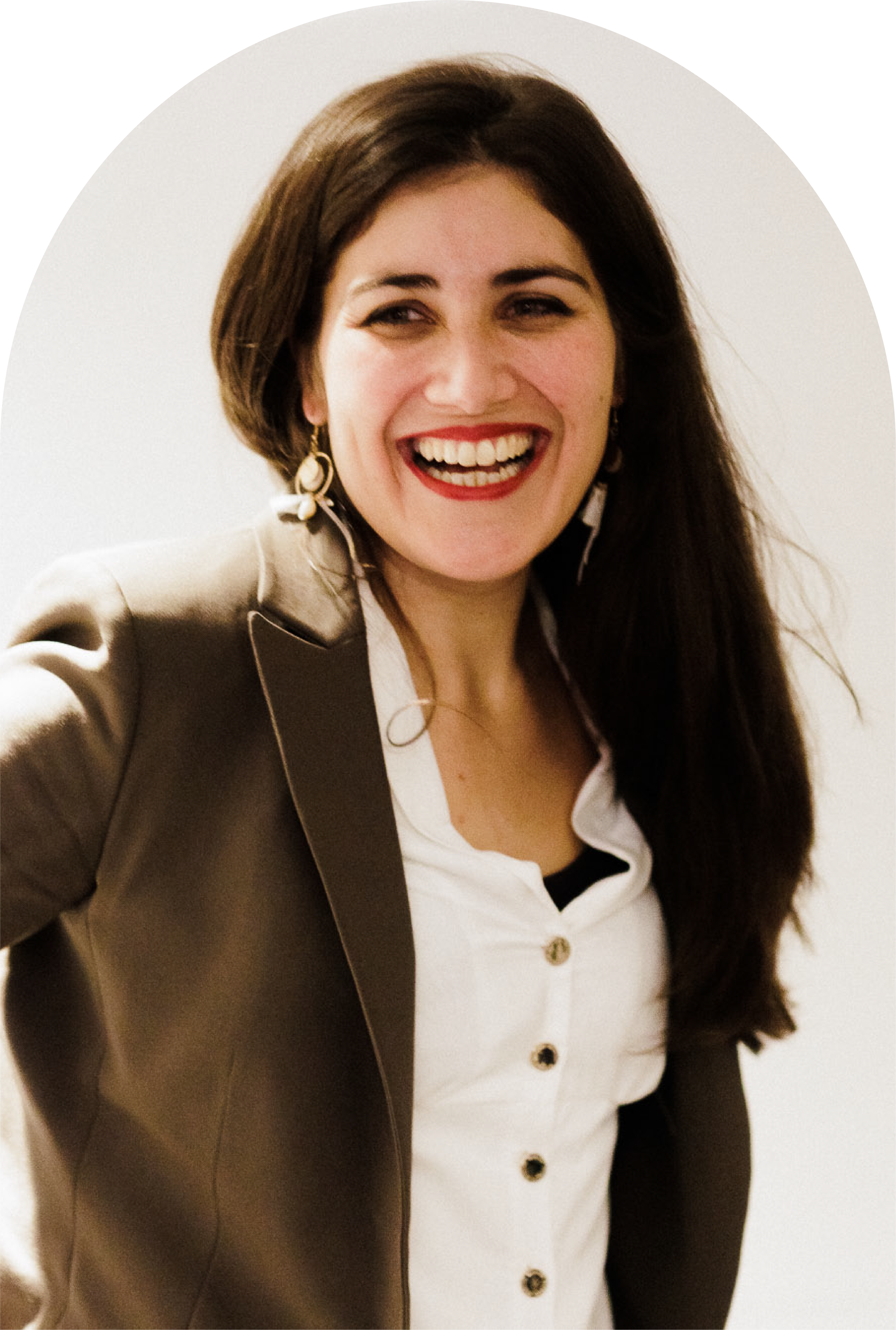 A woman with long dark hair, wearing a white shirt and a beige blazer, smiling brightly, with a white background.