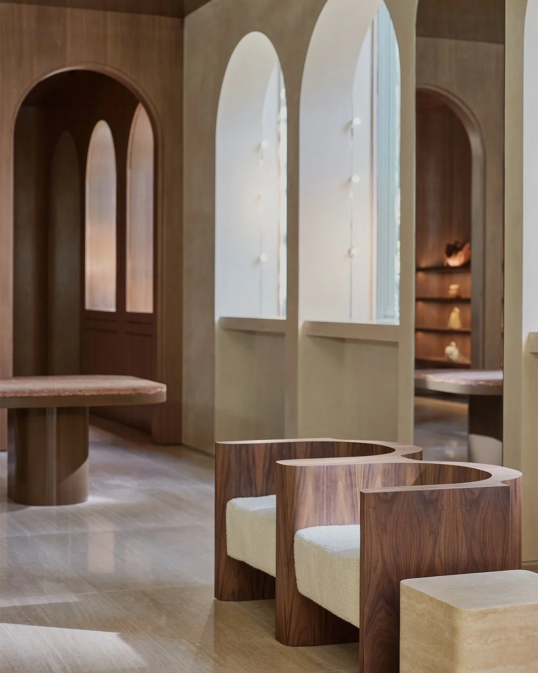 Modern interior space with wooden furniture, arched windows, and a neutral color palette.
