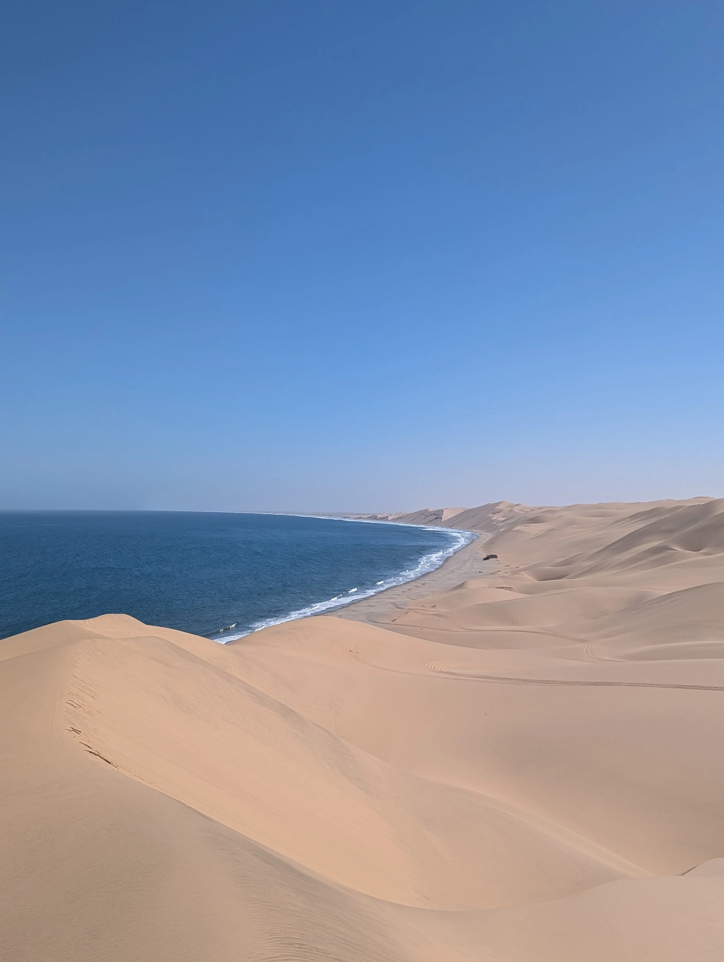 Plage de dunes de sable blanc avec l'océan et un ciel bleu clair
