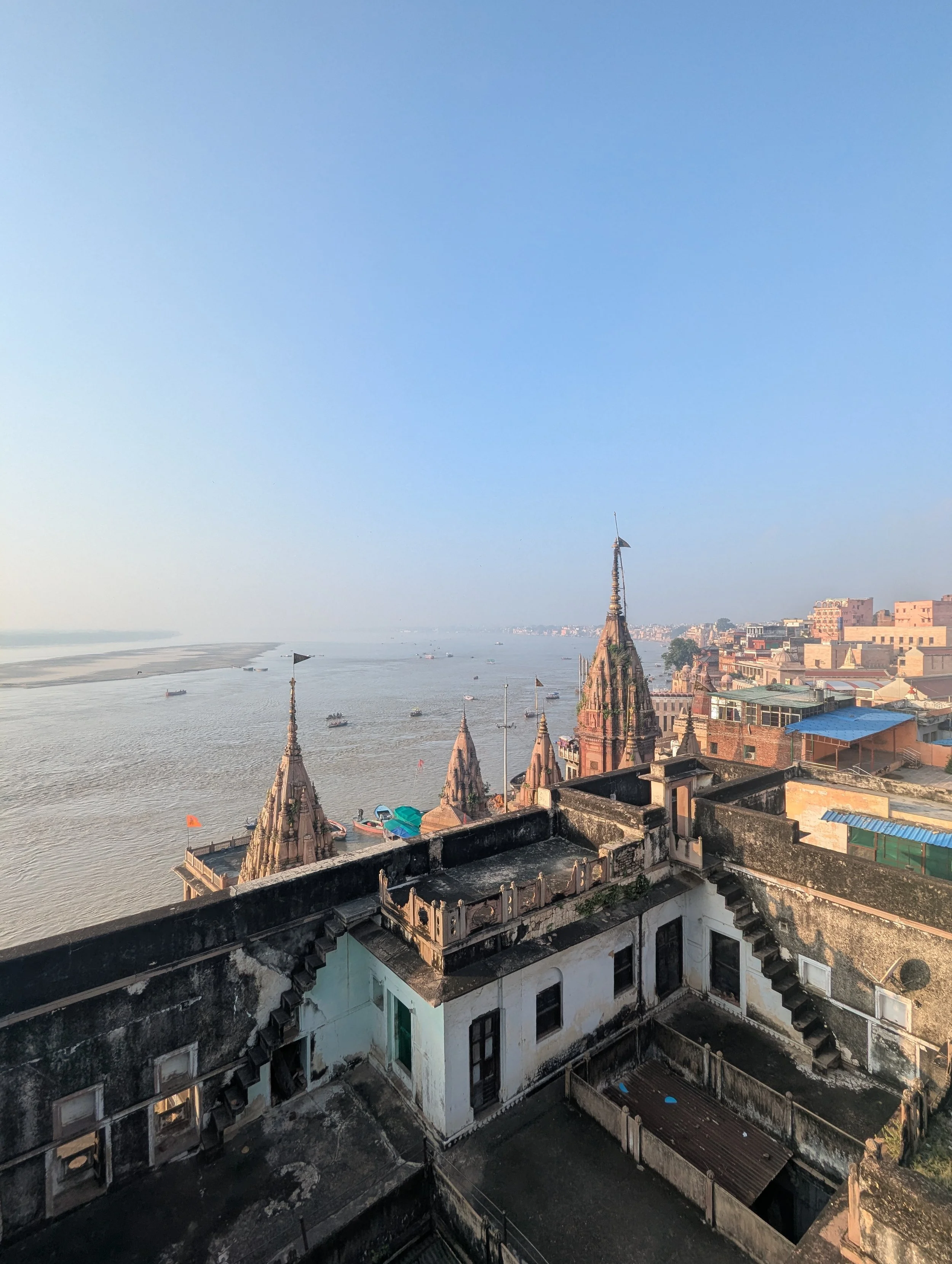 Vues d'une ville ancienne avec des toits en pierre et des tours pointues, au bord d'une rivière avec des bateaux, sous un ciel clair.