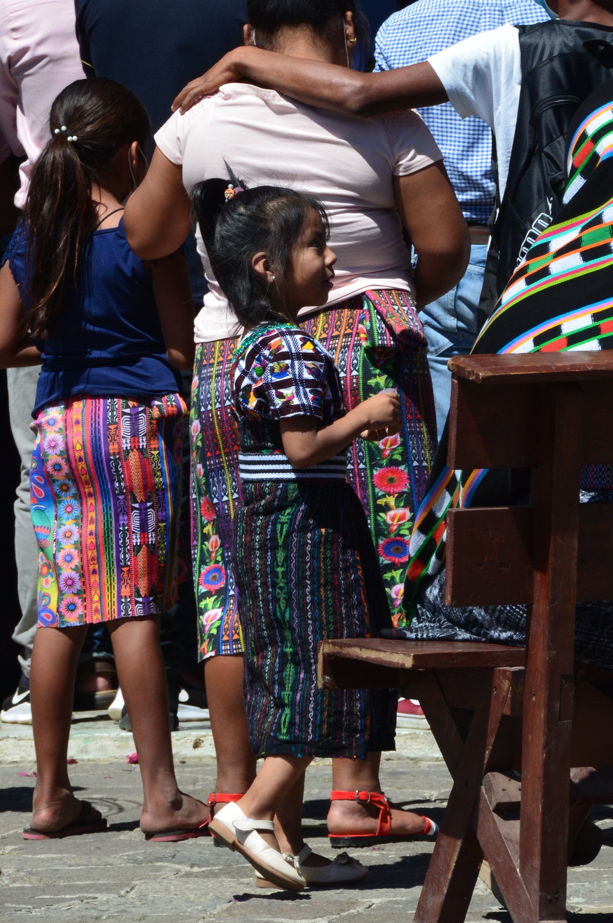 Famille vêtue de tenues traditionnelles mexicaines, avec des tissus colorés et brodés, participent à un événement en plein air.