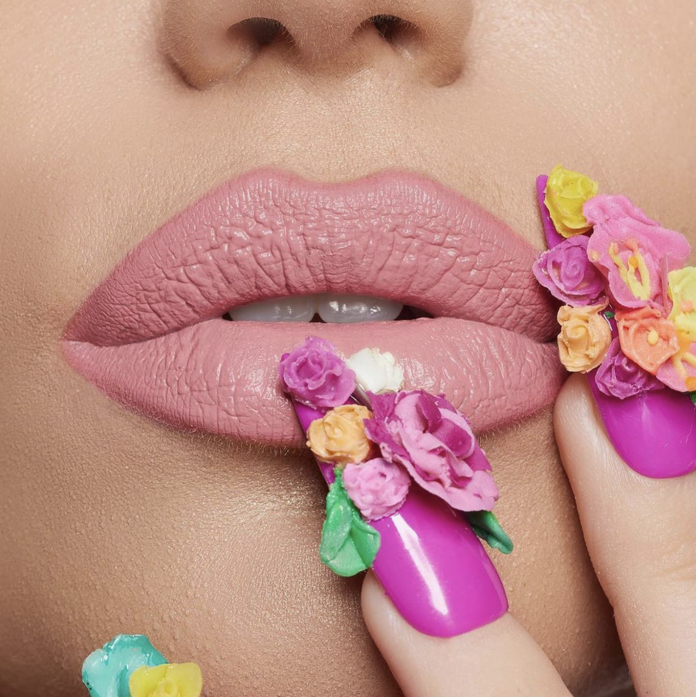 Close-up of pink lips and floral nail art in bright colours
