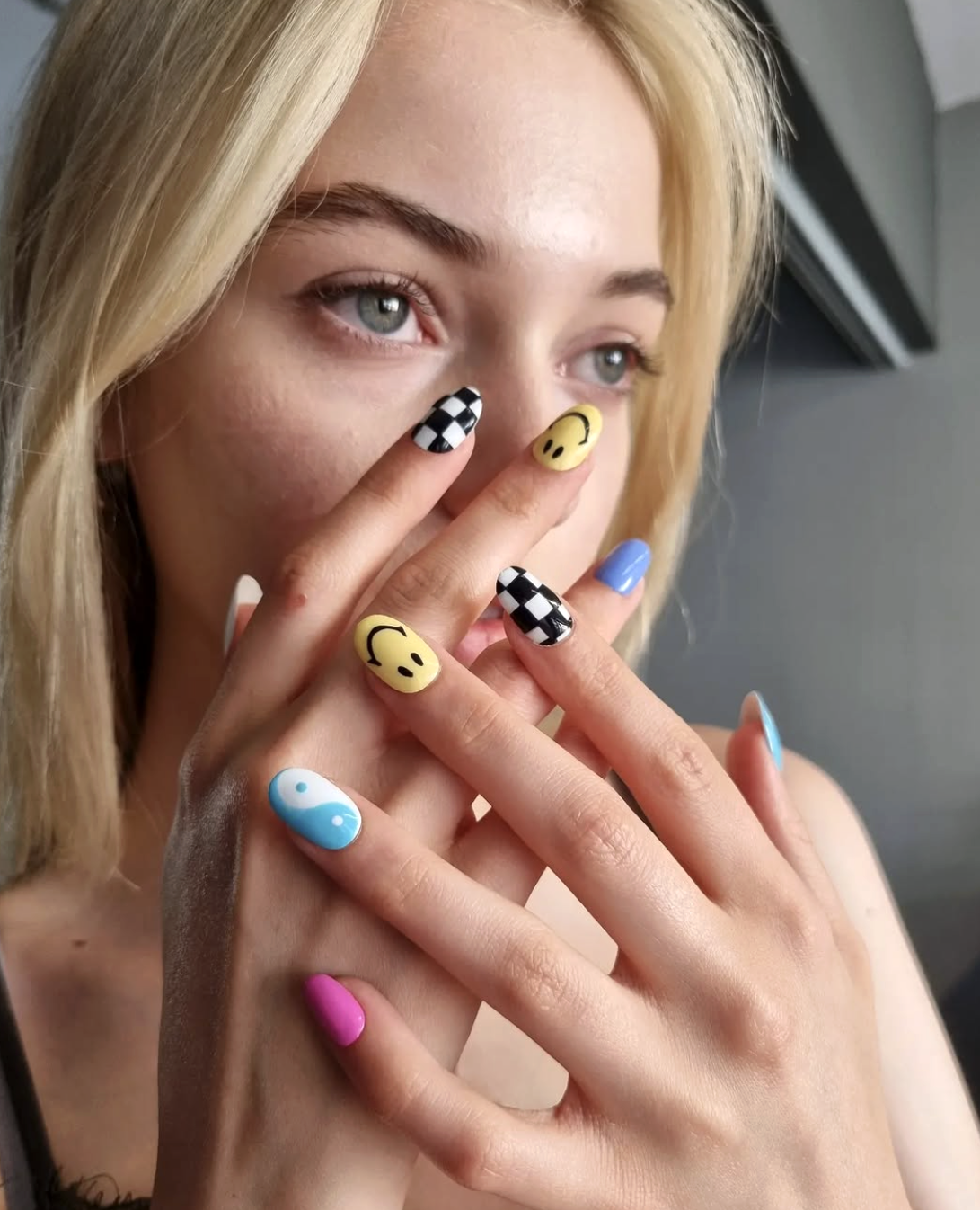 Hands showing playful nail art with patterns and bright colours