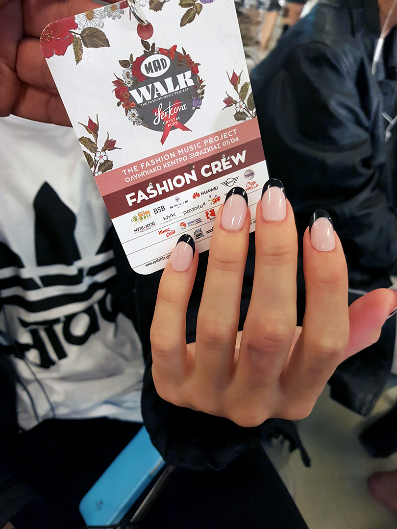 Hand with natural pink manicure holding event pass card