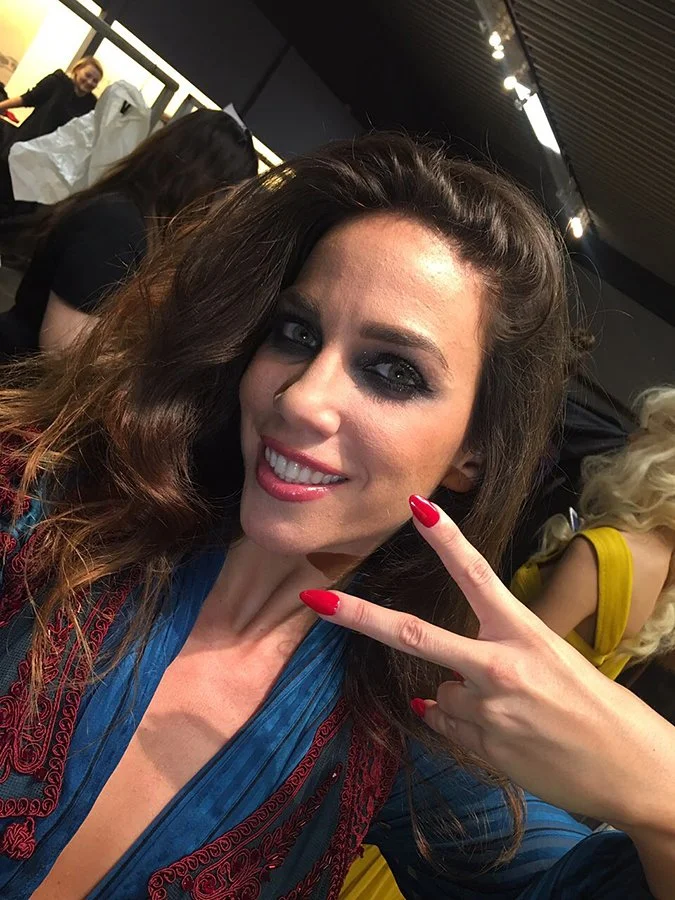 Woman smiling and making peace sign with red manicure