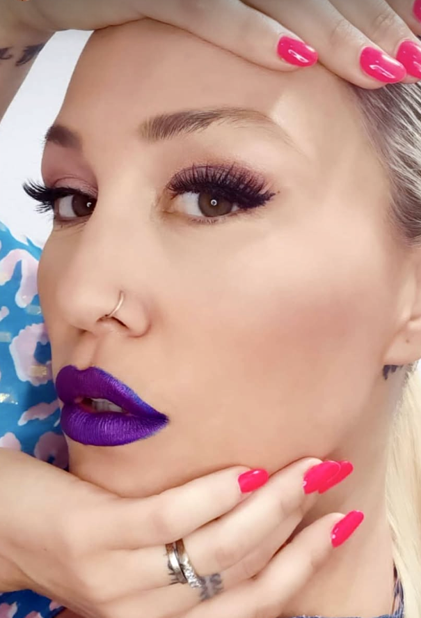 Close-up portrait showing bold purple lipstick and eye makeup