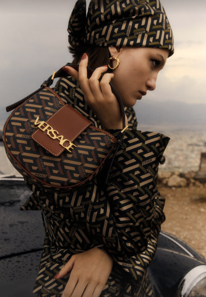 Model wearing patterned outfit and holding small tote bag