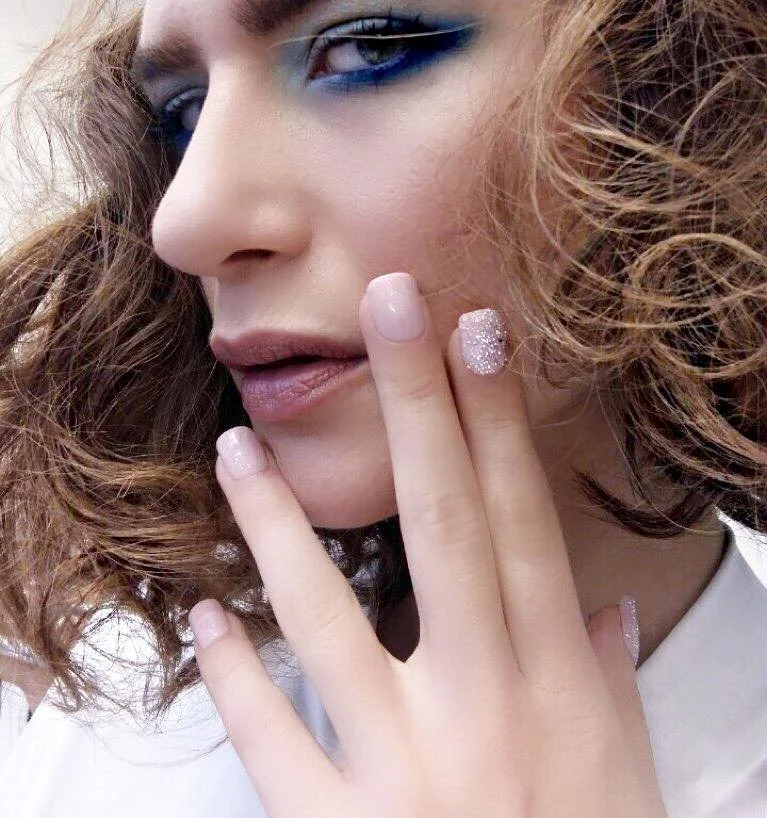 Close-up portrait showing soft pink manicure and eye makeup