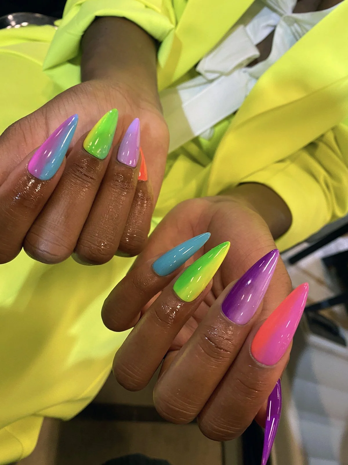 Close-up of hands with long multicolour stiletto nail design
