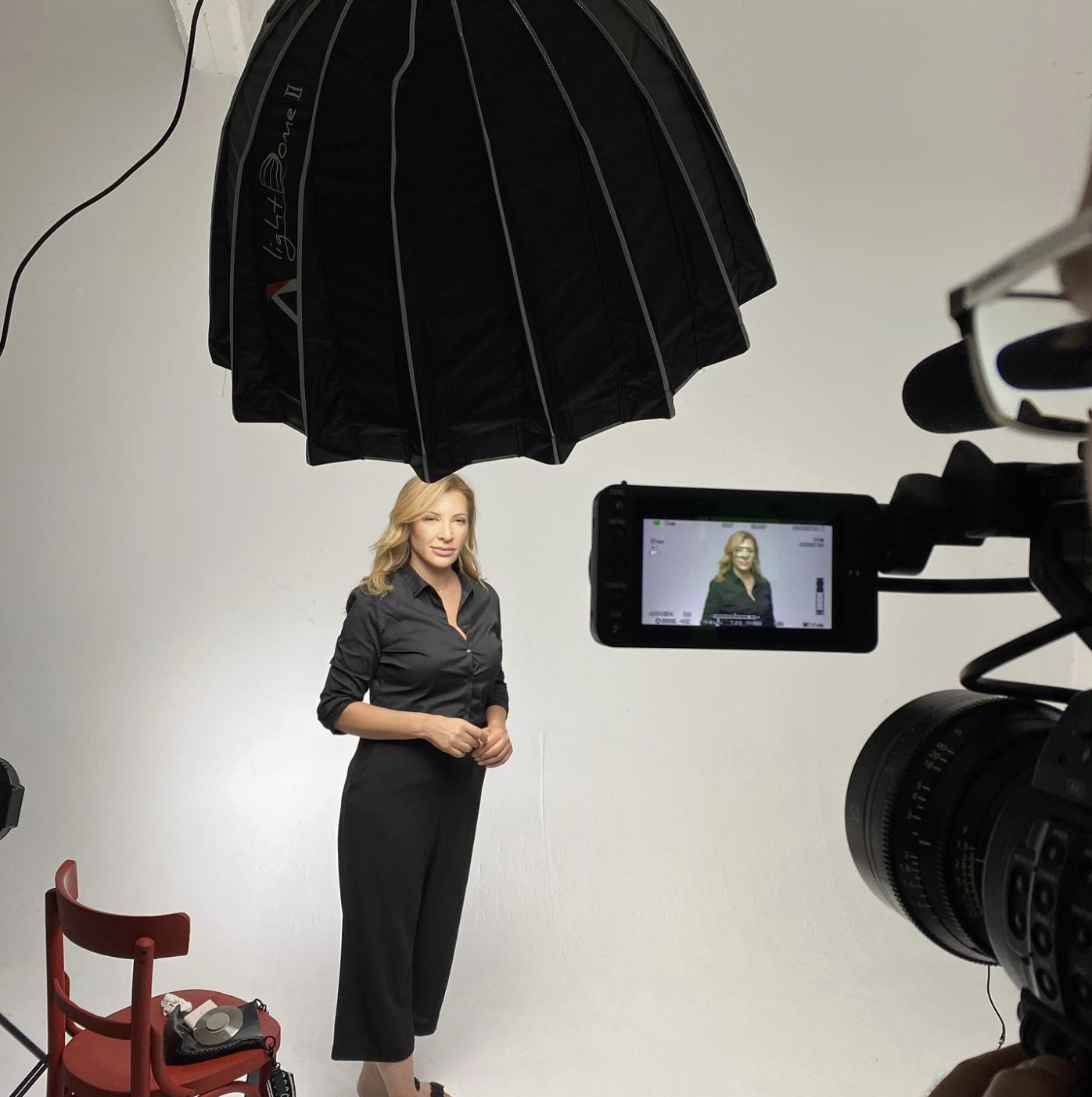 Professional woman posing in studio setup with camera and lighting