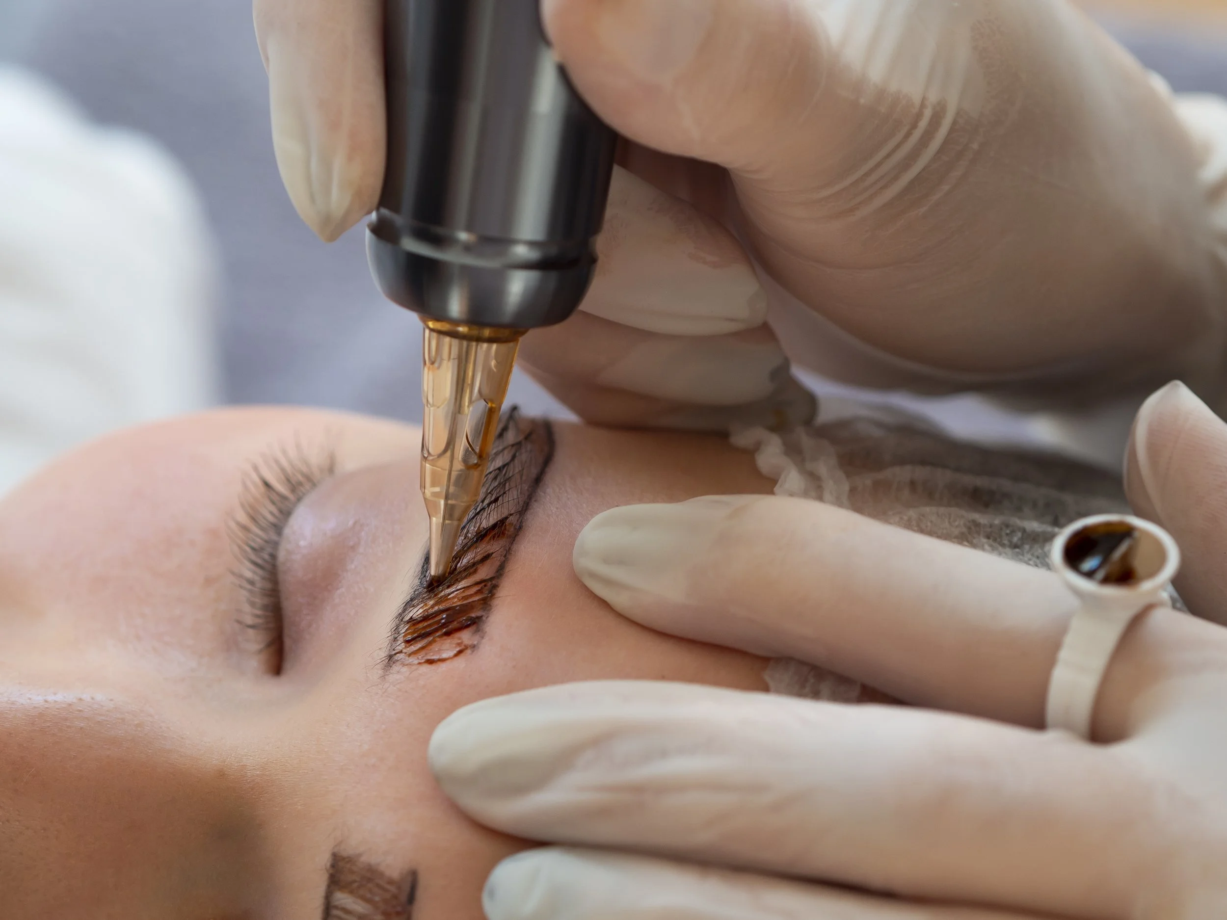 Eyebrow procedure in progress with cosmetic pigment tool