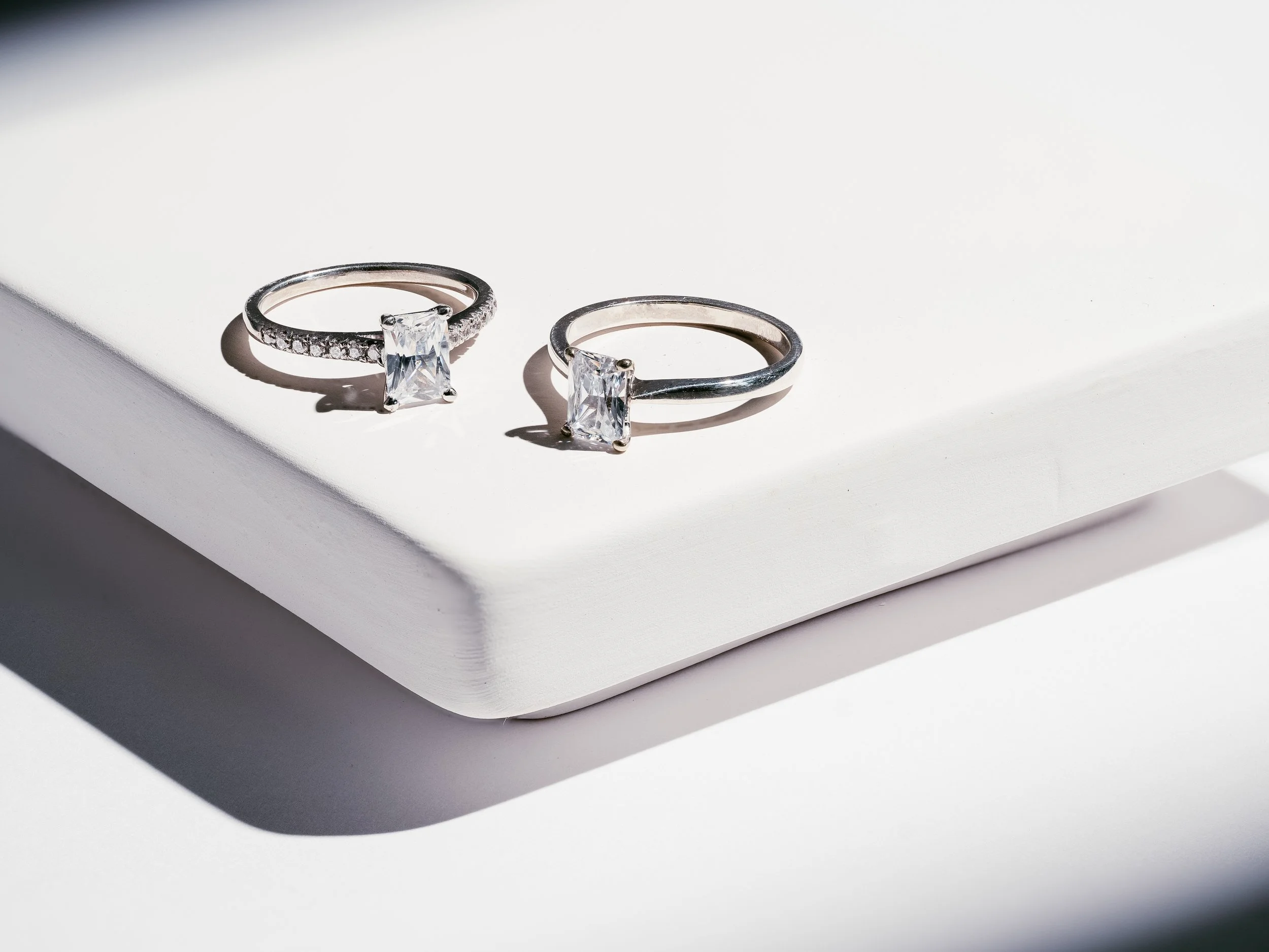 Two silver rings with large rectangular stones on a white surface.