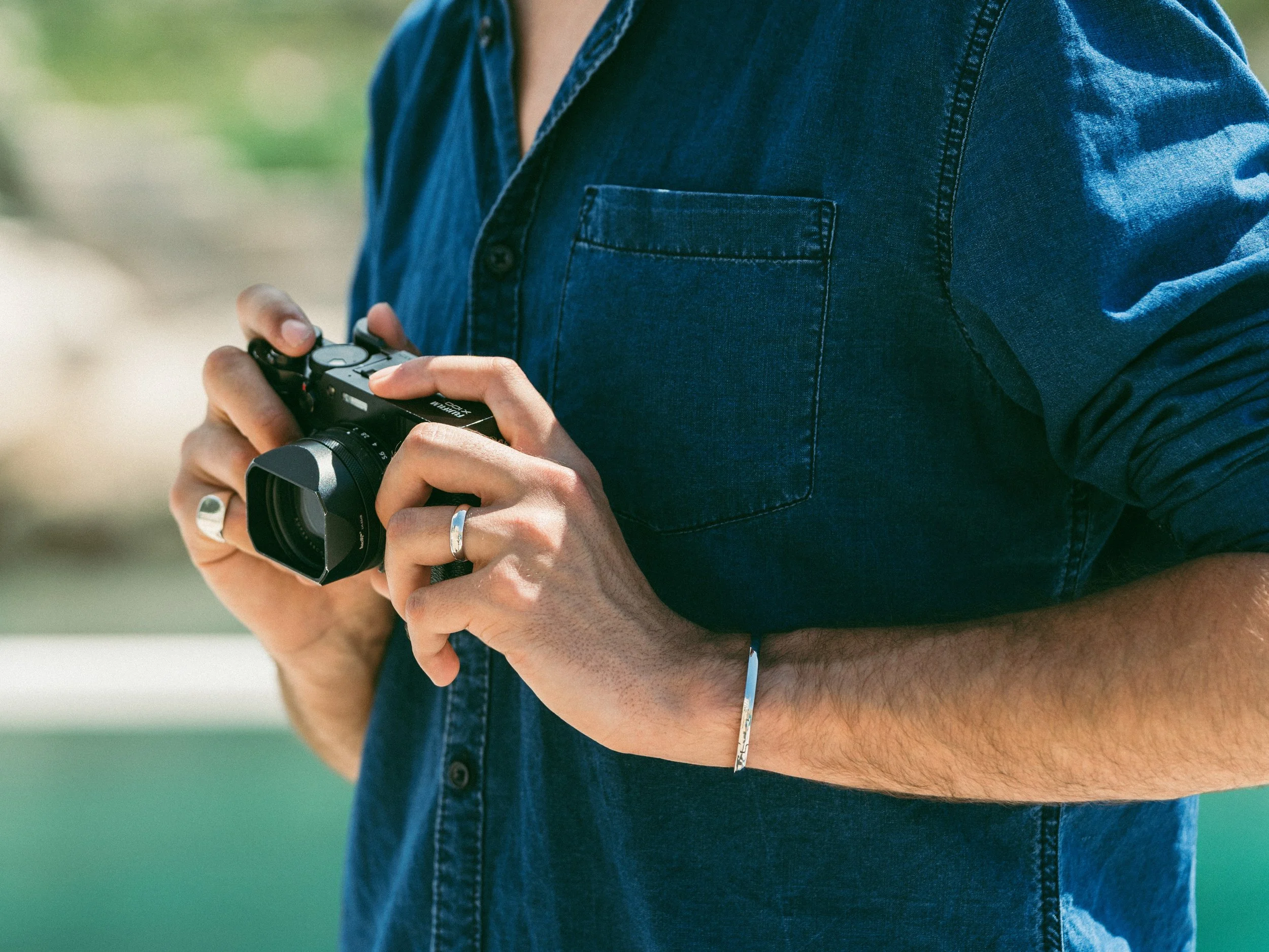 Person holding a camera while wearing a denim shirt
