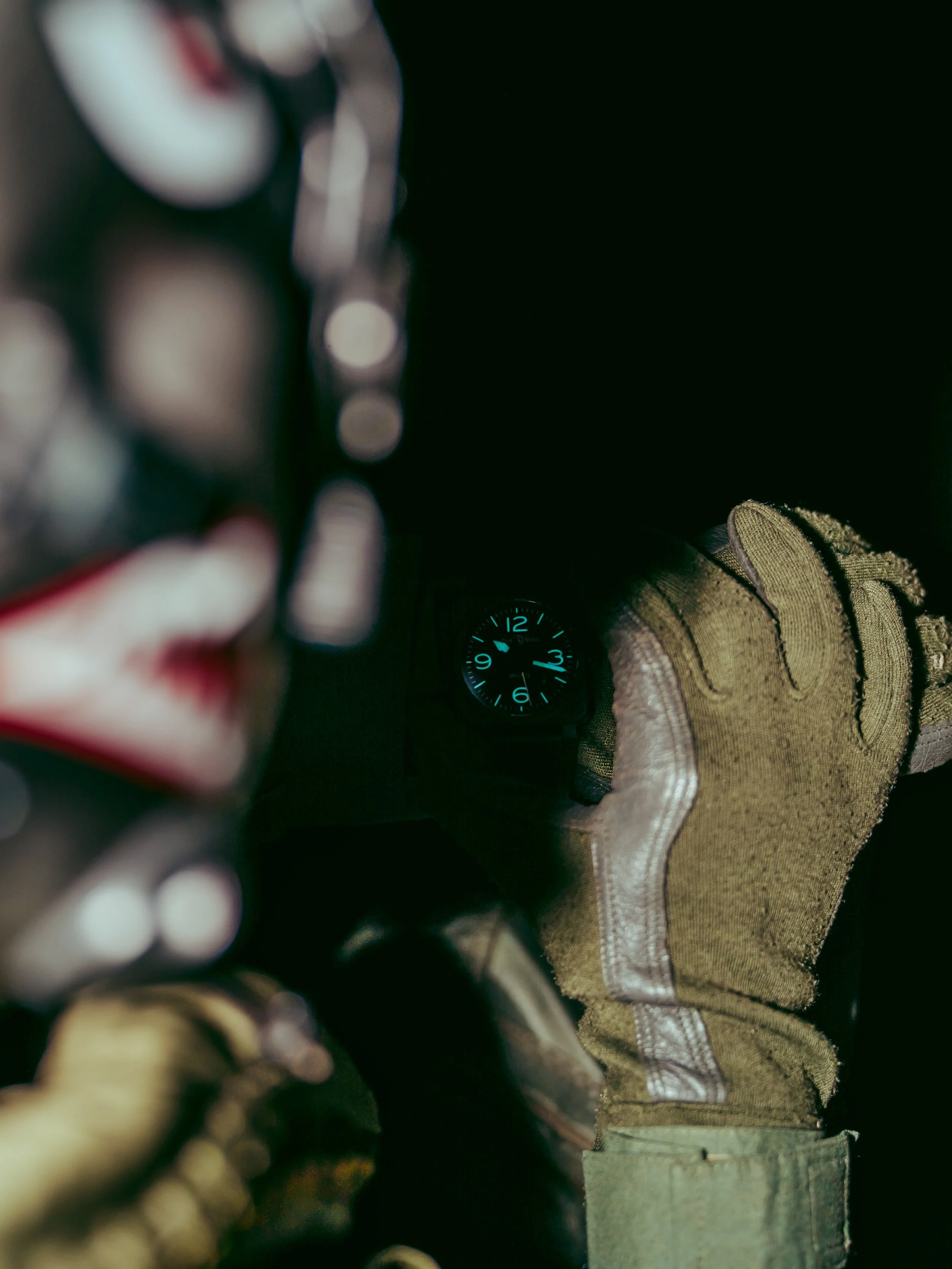Close-up of a person's hand wearing a glove, adjusting a vehicle's dashboard with a small clock showing 02:09.