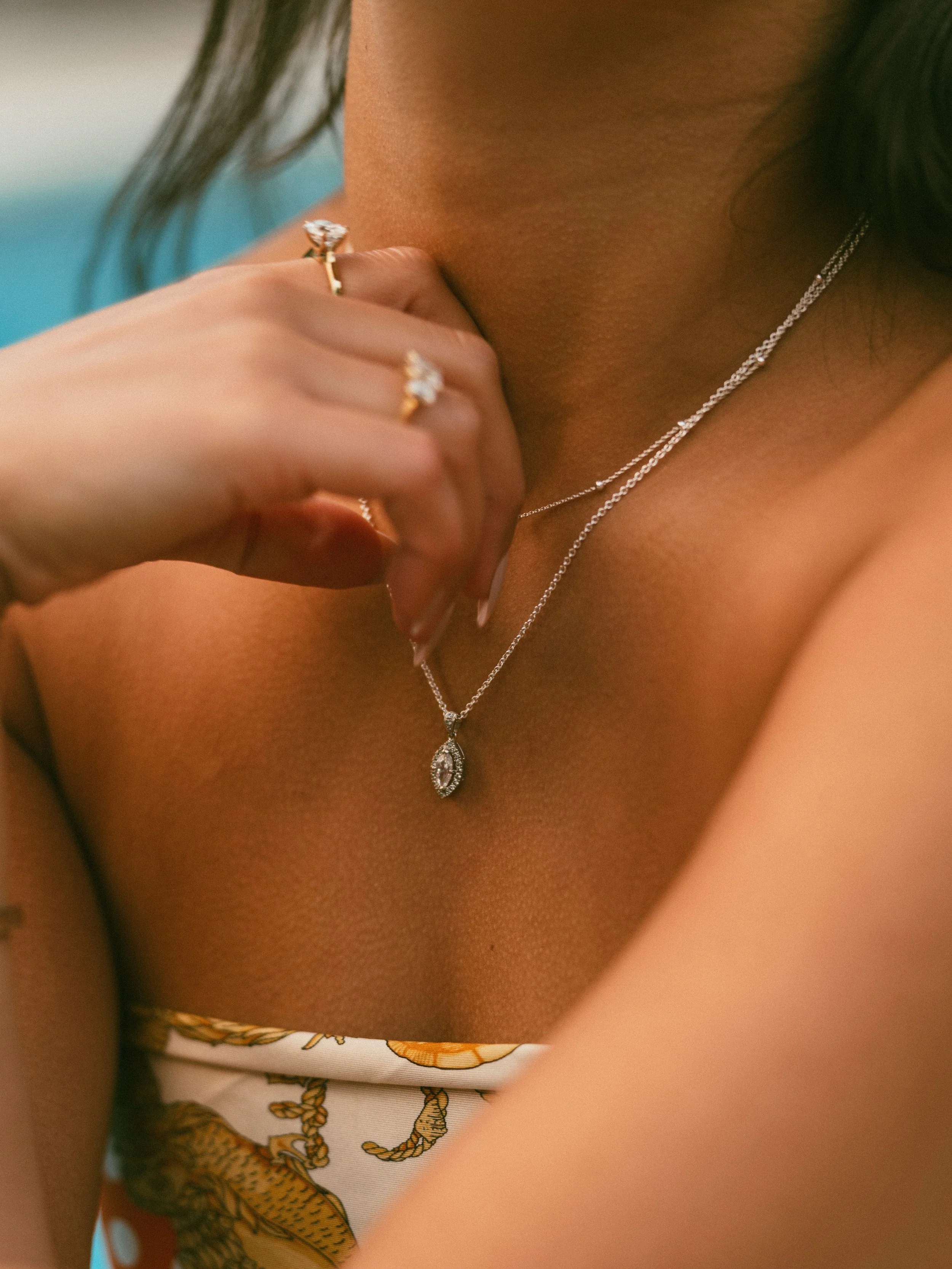 Close-up of a woman wearing diamond jewelry, including a necklace, rings, and a dress with a tiger print.