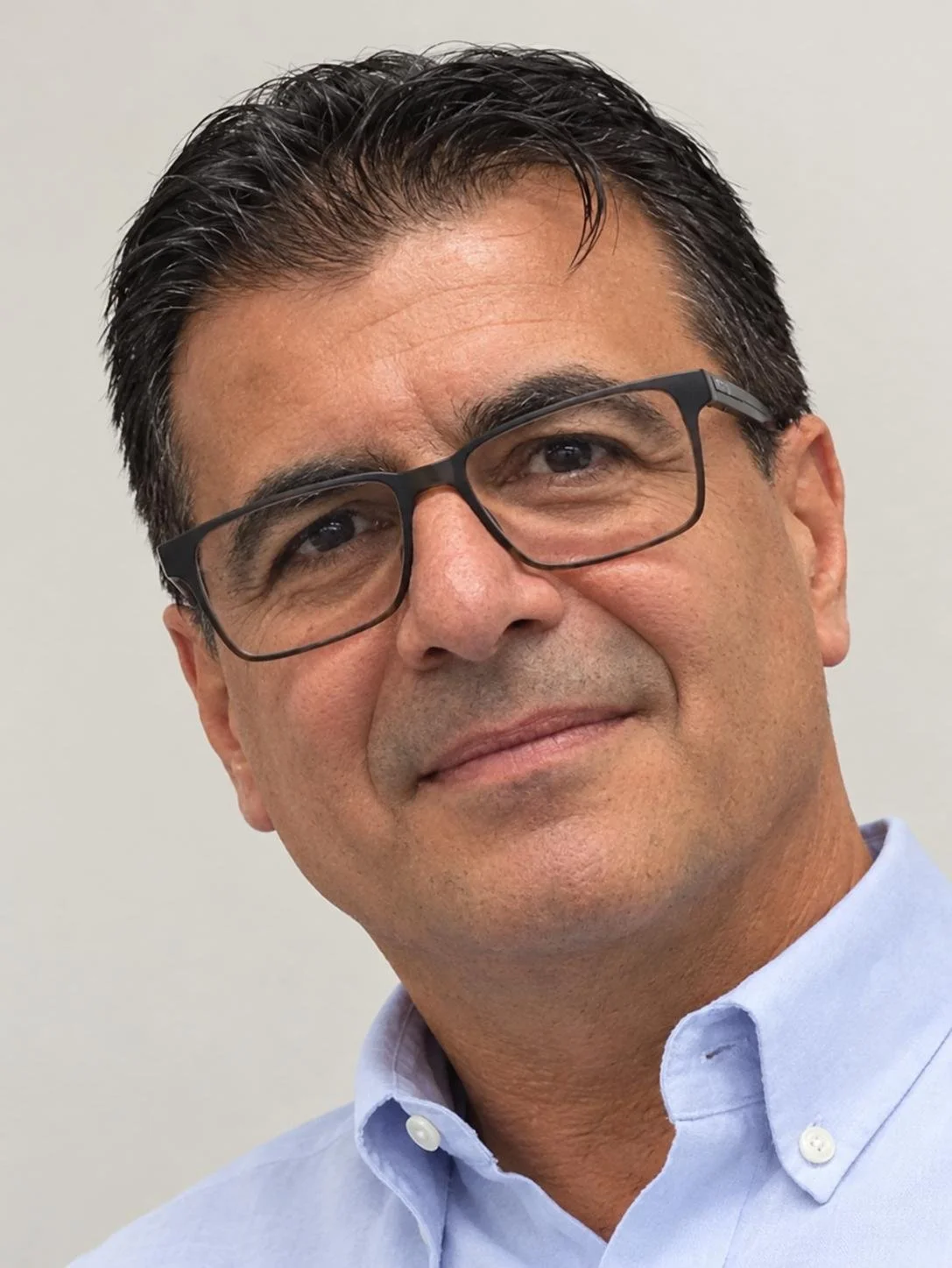 Image of a man with a blue shirt, brown hair and glasses