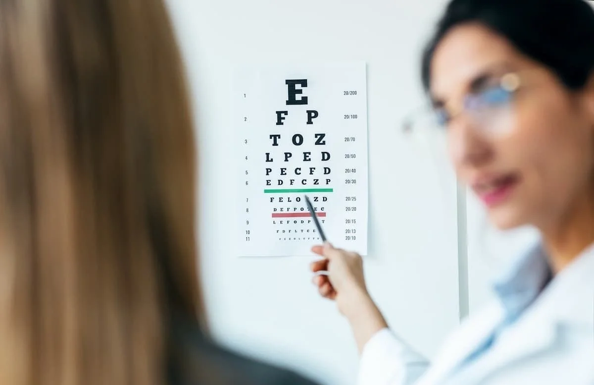 Ottico che spiega un cartello con un test visivo a un paziente