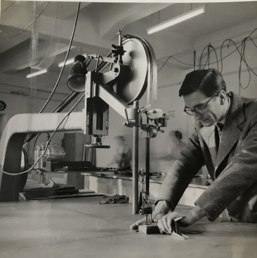 My grandfather Karl at the sewing machine at the tailoring atelier  in an elegant suit wearing glasses