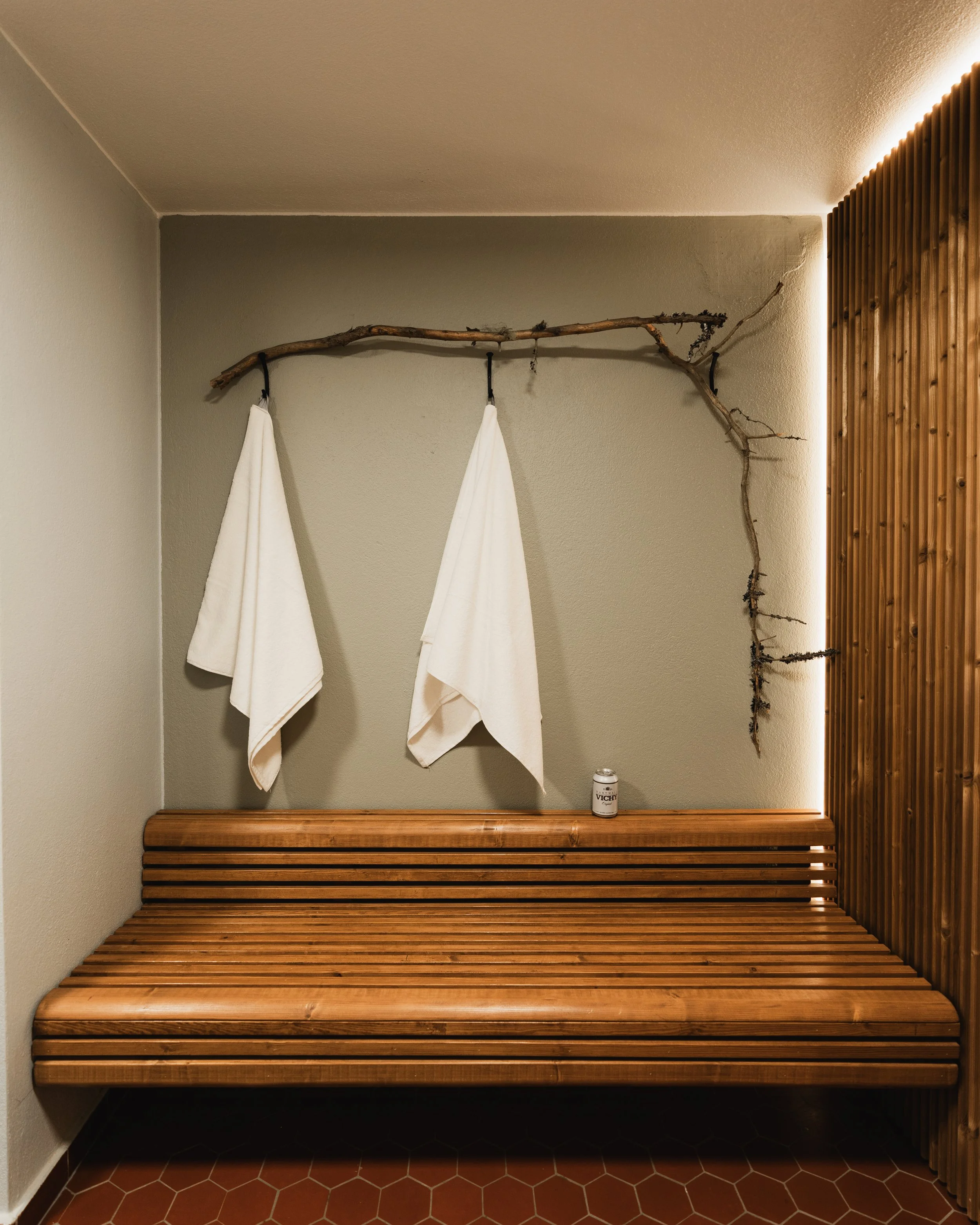 Sauna in Rovaniemi. Sauna with two white towels hanging from a branch and a can of Vichy on the wooden bench.