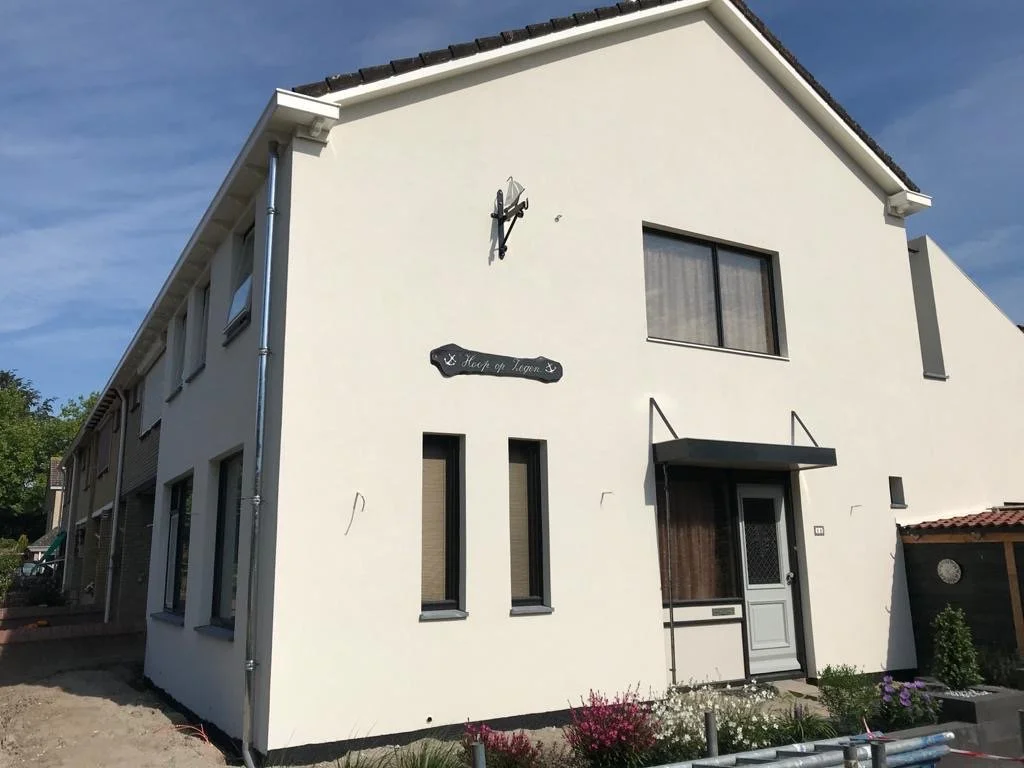 Moderne houten gebouw met grote glaswand, gelegen in een bergachtig landschap met lage vegetatie.