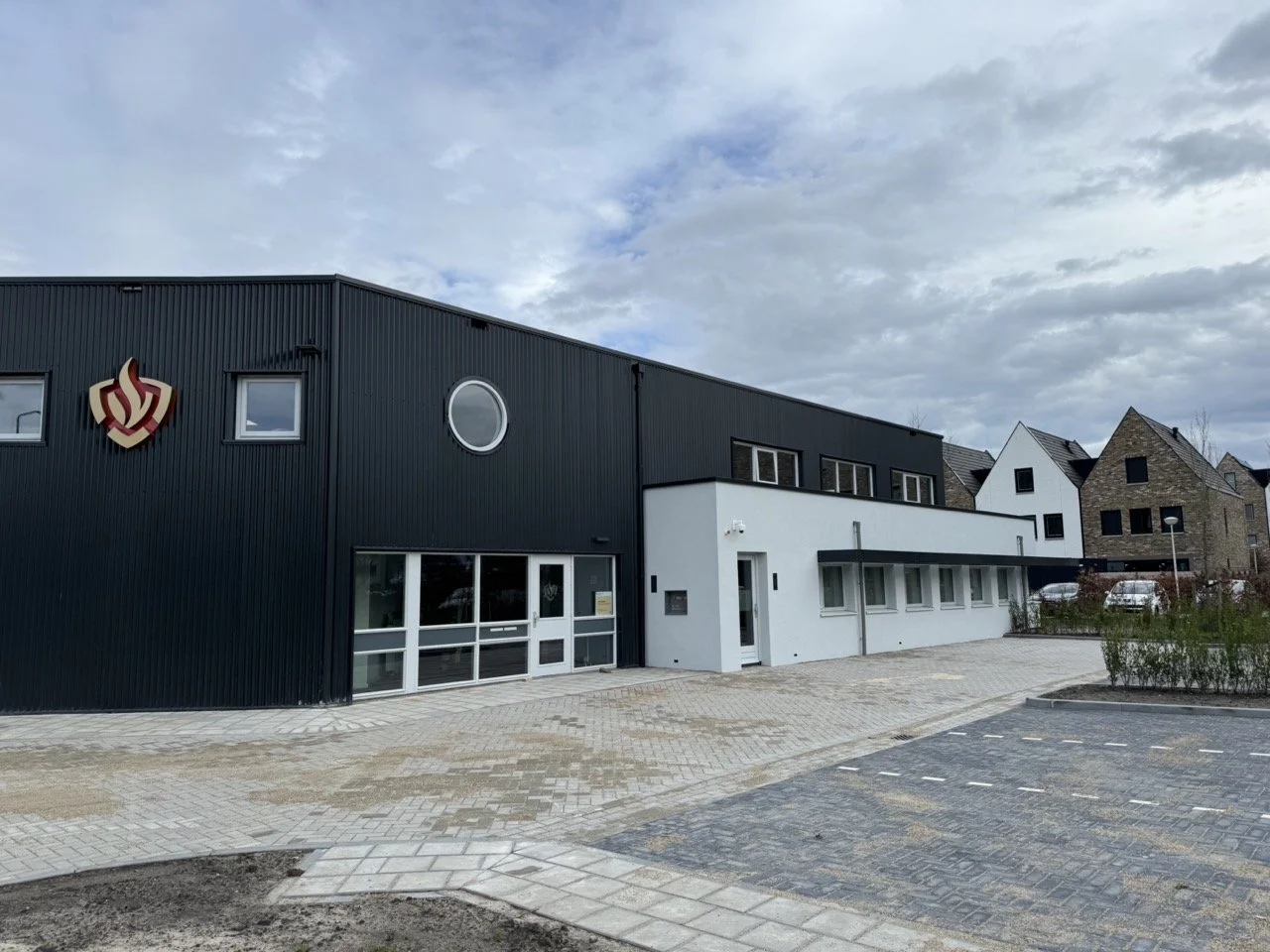 Uitzicht op een bergmeer met groene heuvels en hoge bergen op de achtergrond, onder een bewolkte hemel.