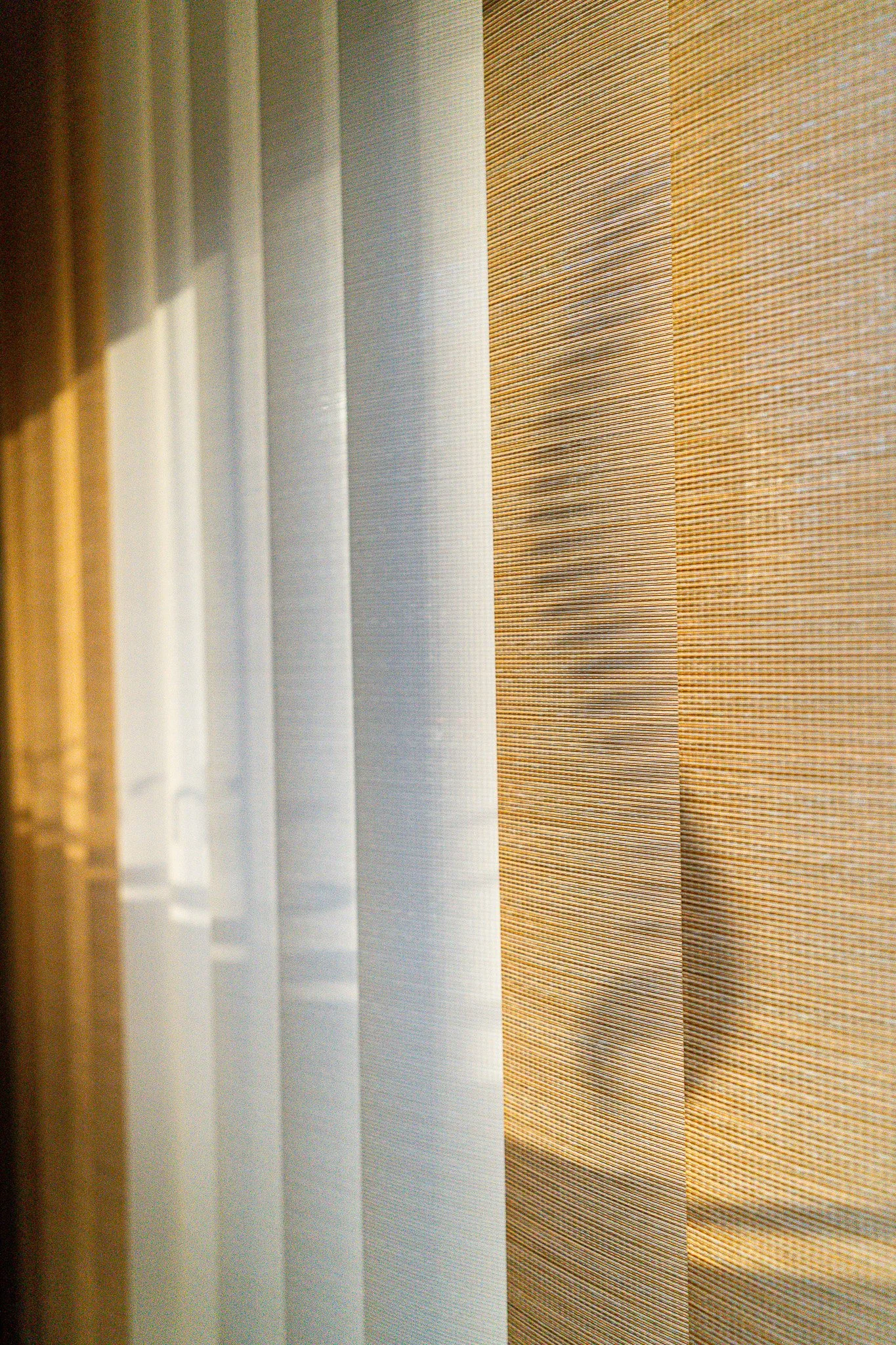 Close-up of vertical blinds with alternating white, beige, and brown fabric.