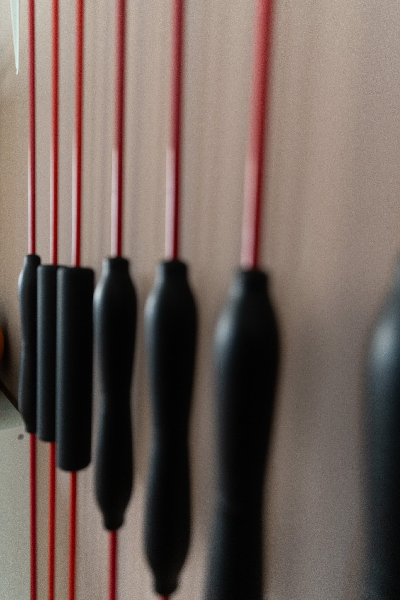 A close-up of black-handled screwdrivers with red shafts hanging on a vertical board.