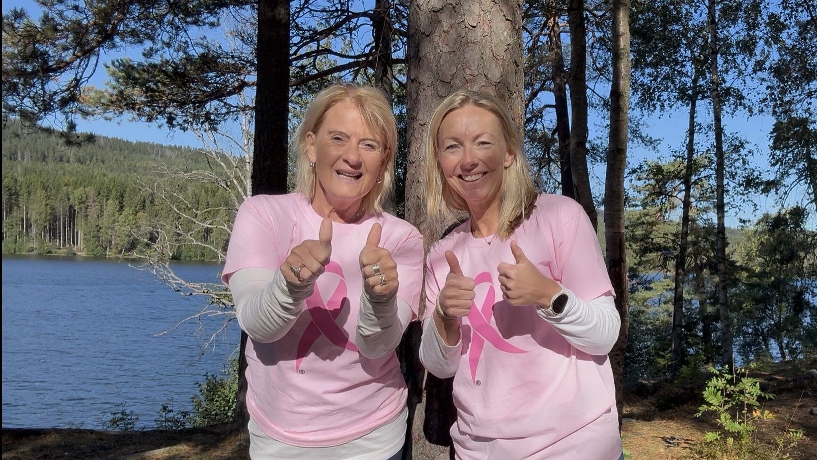 Anne og Inger-Marie med tommel opp for påmelding til webinar, rosa sløyfe aksjonen.