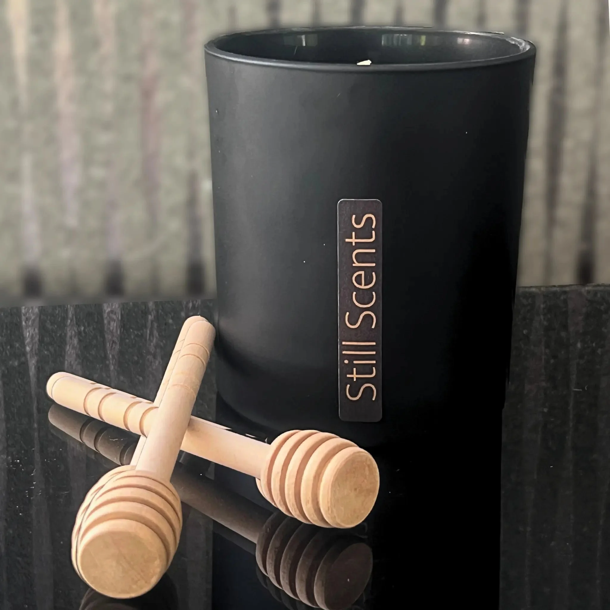 Matte black candle with honey stirrers.