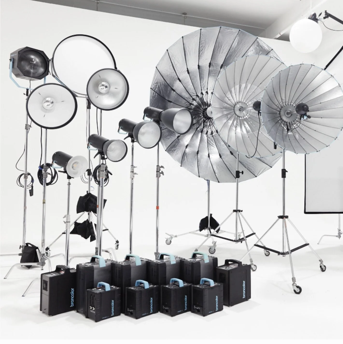Photography studio lighting equipment, including softboxes, umbrellas, and portable power sources, arranged in a professional setup on a white backdrop.