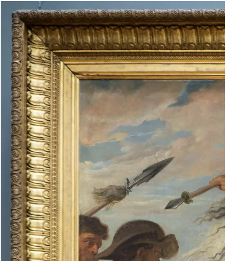 Close-up of a historical painting with a detailed ornate gold frame, depicting a scene with people, a spear, and a cloudy sky.