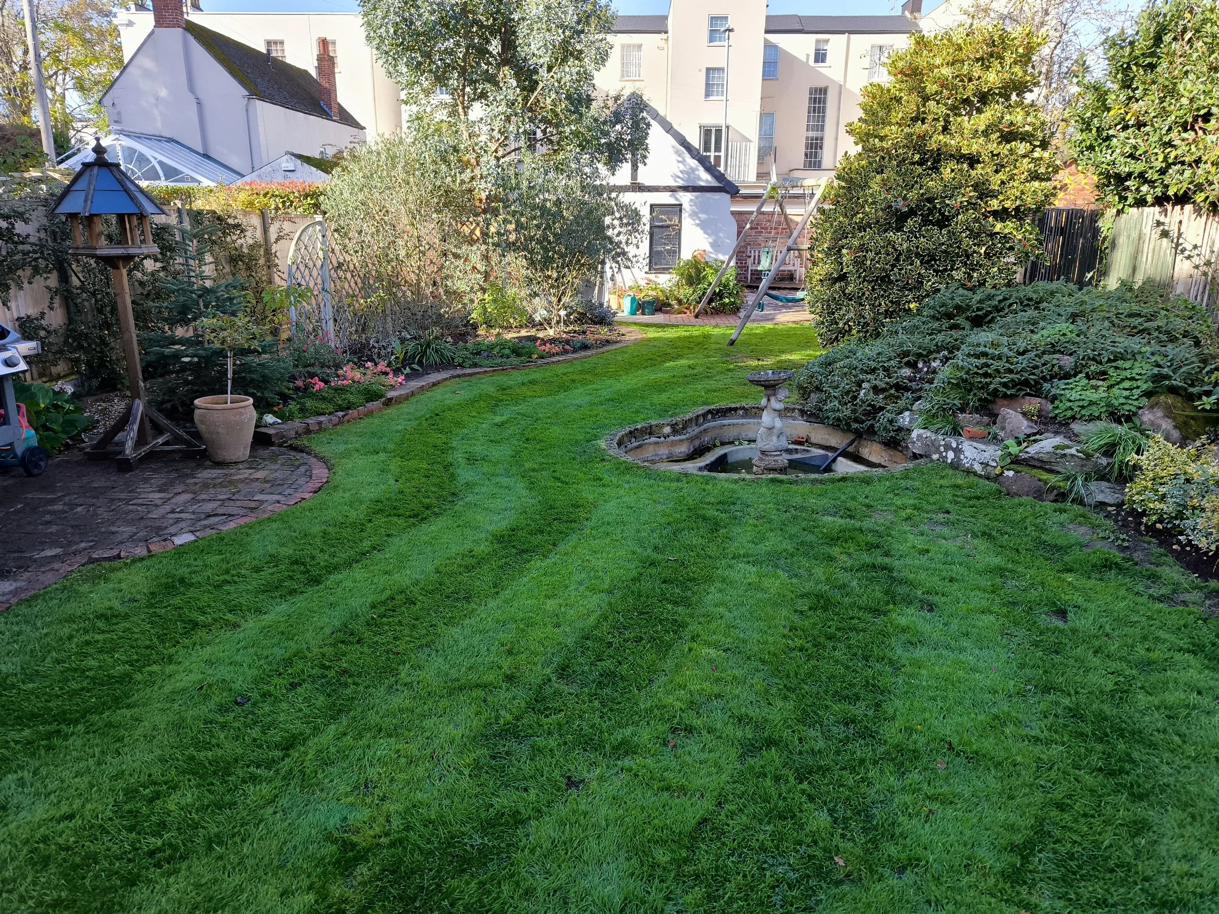 Freshly mowed garden with a neatly trimmed lawn and a decorative water feature creating a serene outdoor space.