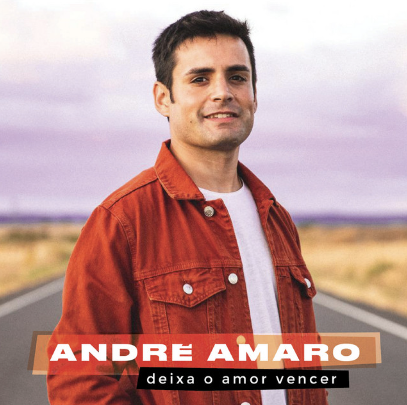 A young man with short dark hair wearing a red jacket and white T-shirt, standing on an open road with a sunset sky in the background. Text on the image says 'André Amaro' and 'deixa o amor vencer'.
