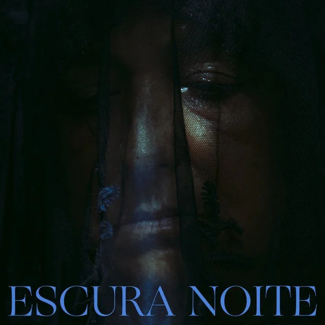A close-up of a woman's face partially obscured by dark mesh fabric, with the words 'ESCURA NOITE' in blue at the bottom.