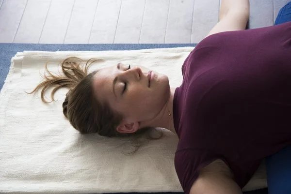 close up photo of a yoga student looking serene in savasana