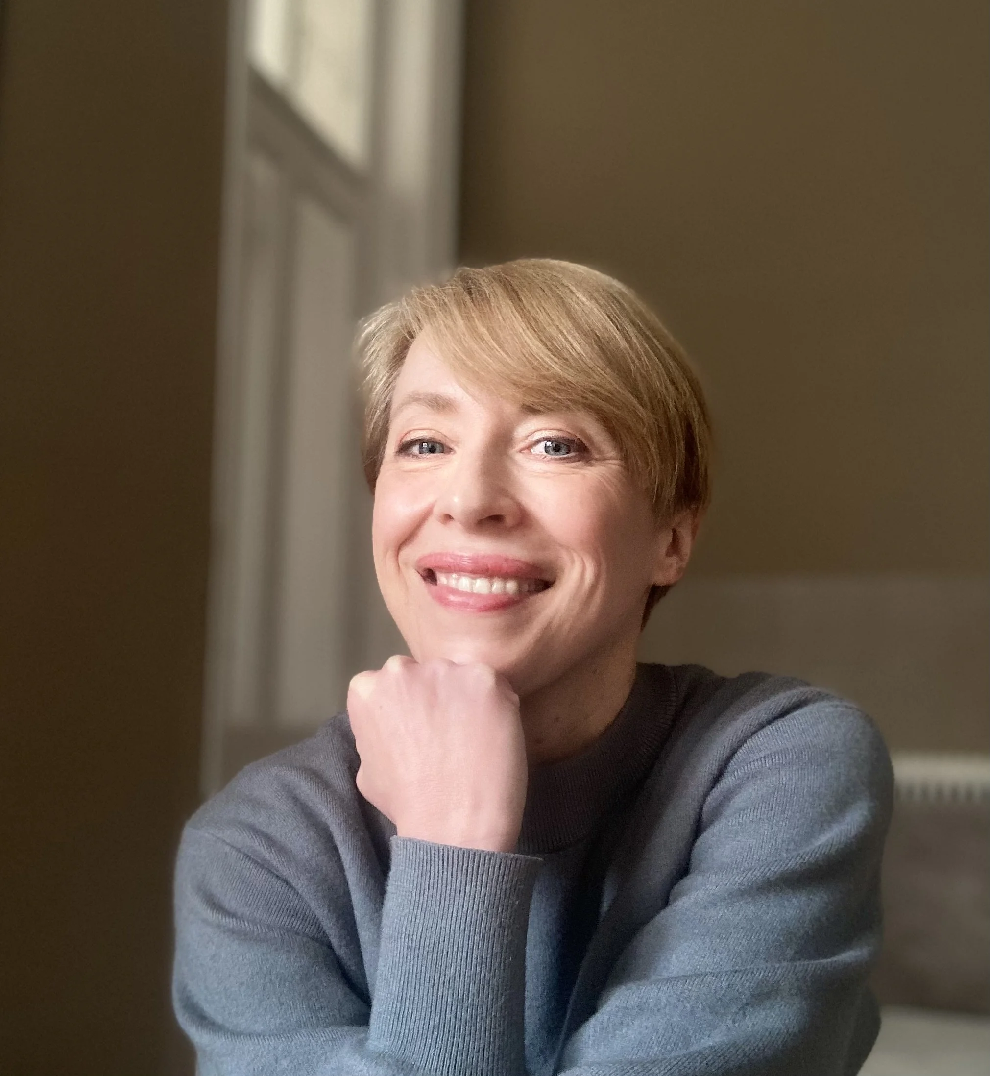 Nahaufnahme einer freundlich blickenden Frau mit kurzen, blonden Haaren.