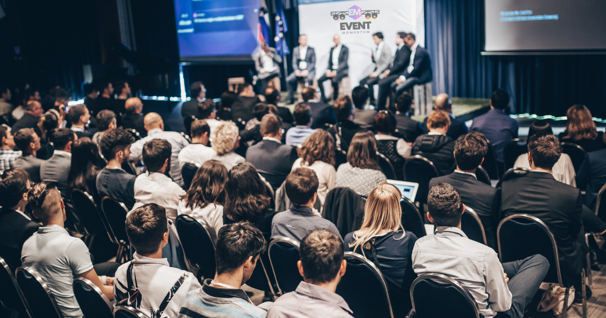Busy business conference with delegates watching a panel discussion at a well-attended event. | Event Momentum