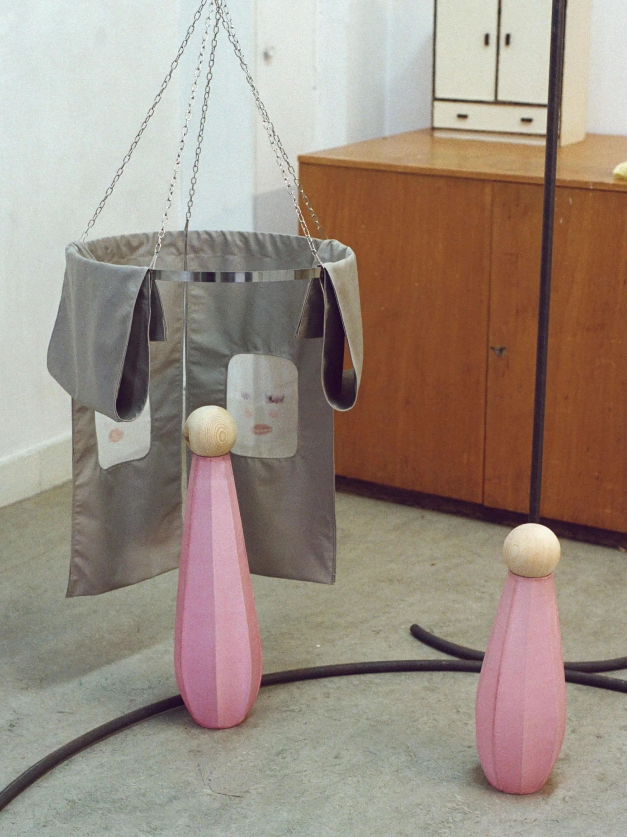 Attend! (2026) for The Act of Dressing @syzygy_collective 

Attend! is an installation comprising two satin and wood figures and suspended textile panels hung on chains. The figures stand at the edge of an enclosure that opens downward; its fabric pa
