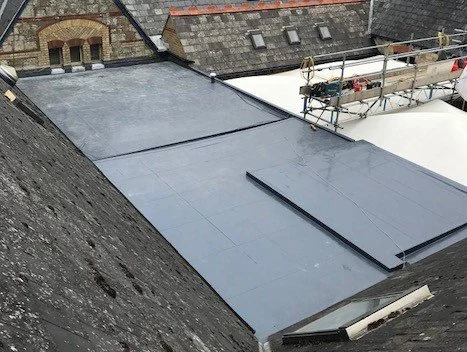 Flat rooftop with roofing materials and scaffolding on the right side.