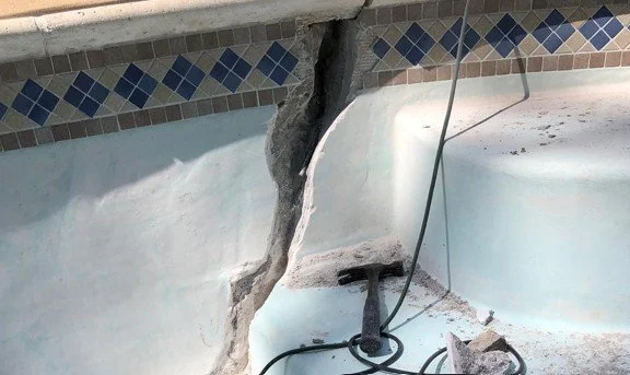 Technician repairing a large crack in an inground gunite pool to stop leaks and prevent damage.